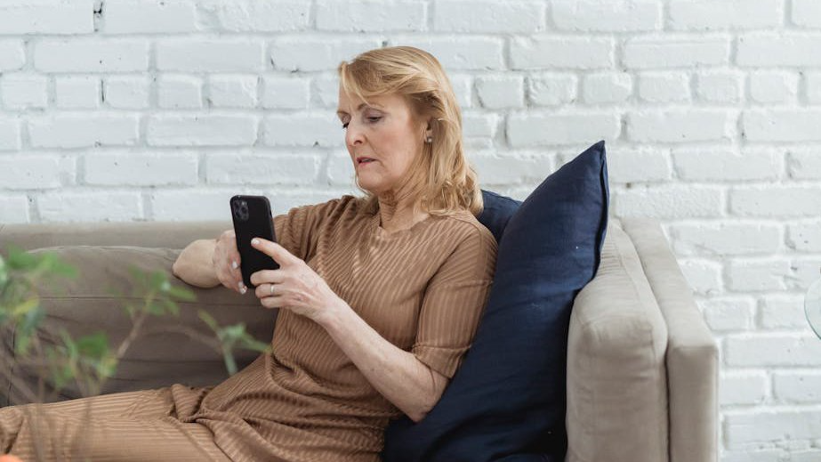 Elderly woman chatting on smartphone on sofa