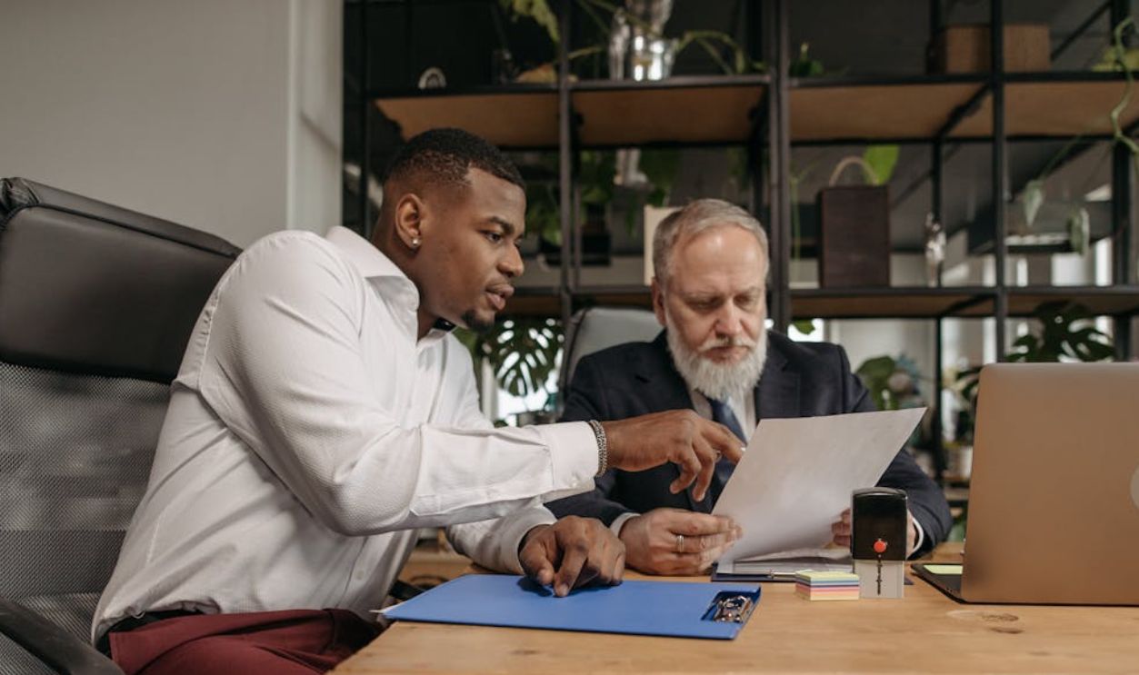 Two businessmen reviewing documents together in a modern office environment.