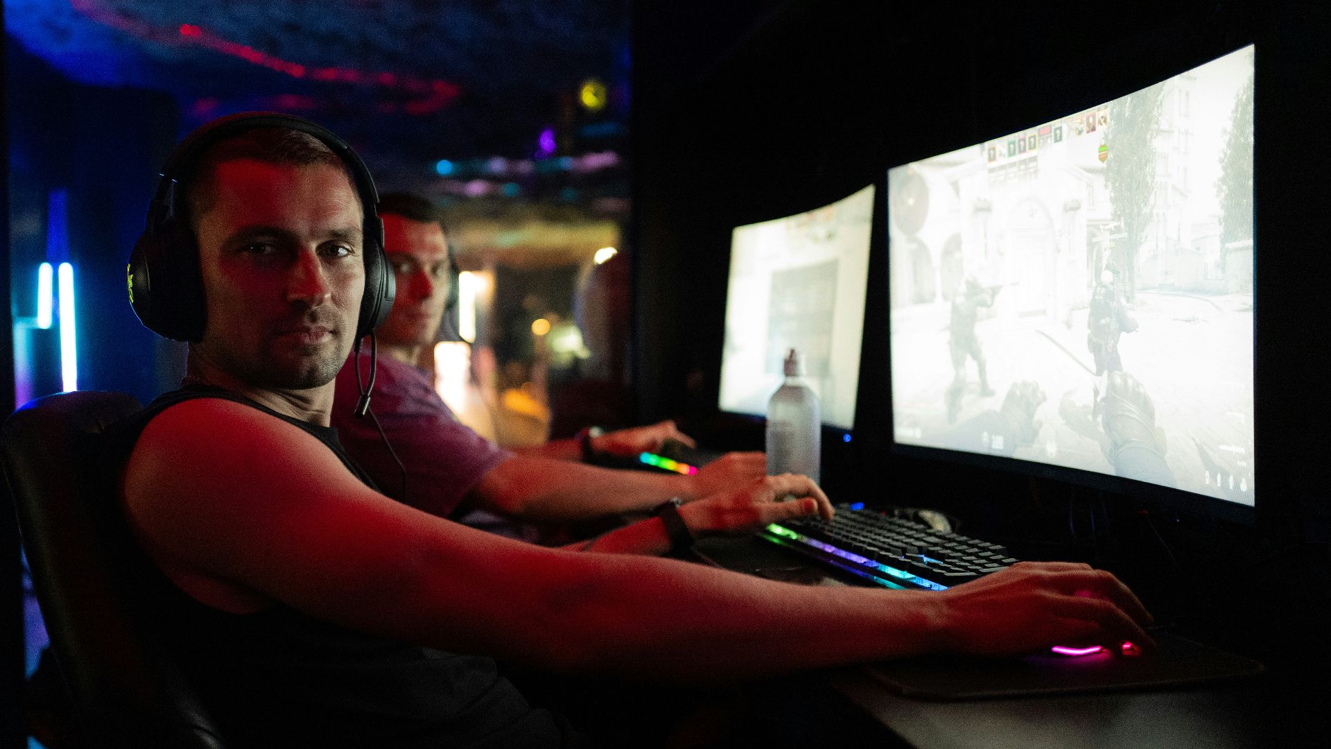 Men playing video games in a dimly lit room.