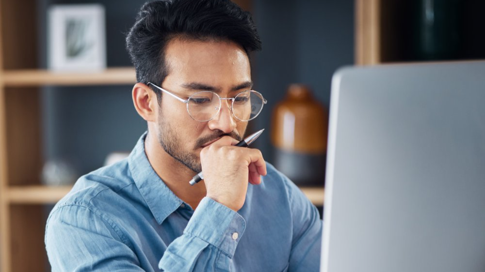Serious, business man and thinking on computer in office
