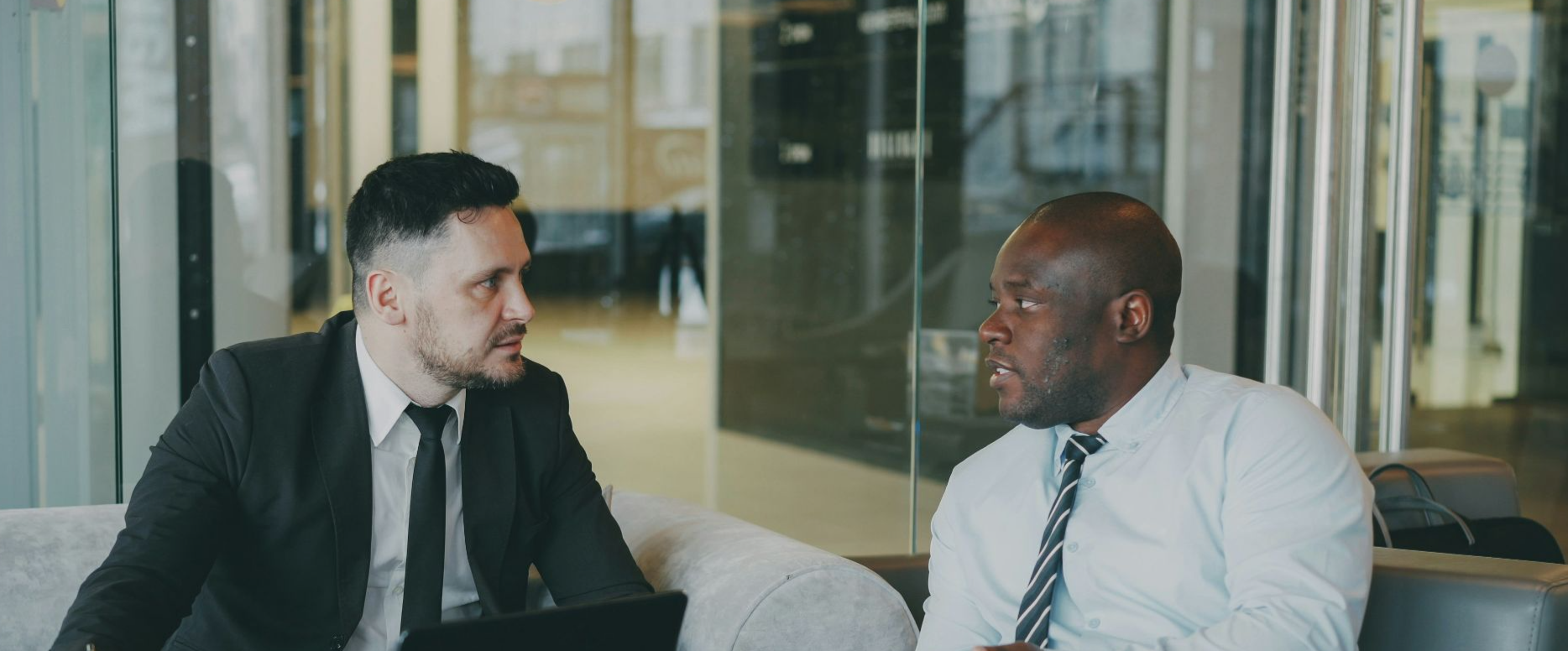 Two businessmen in suits talking in a modern office.
