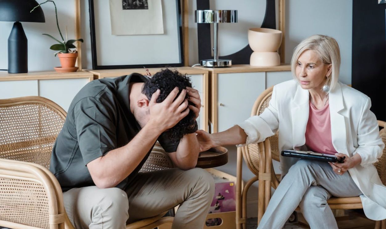 A supportive therapist provides comfort during a counseling session in a cozy office.