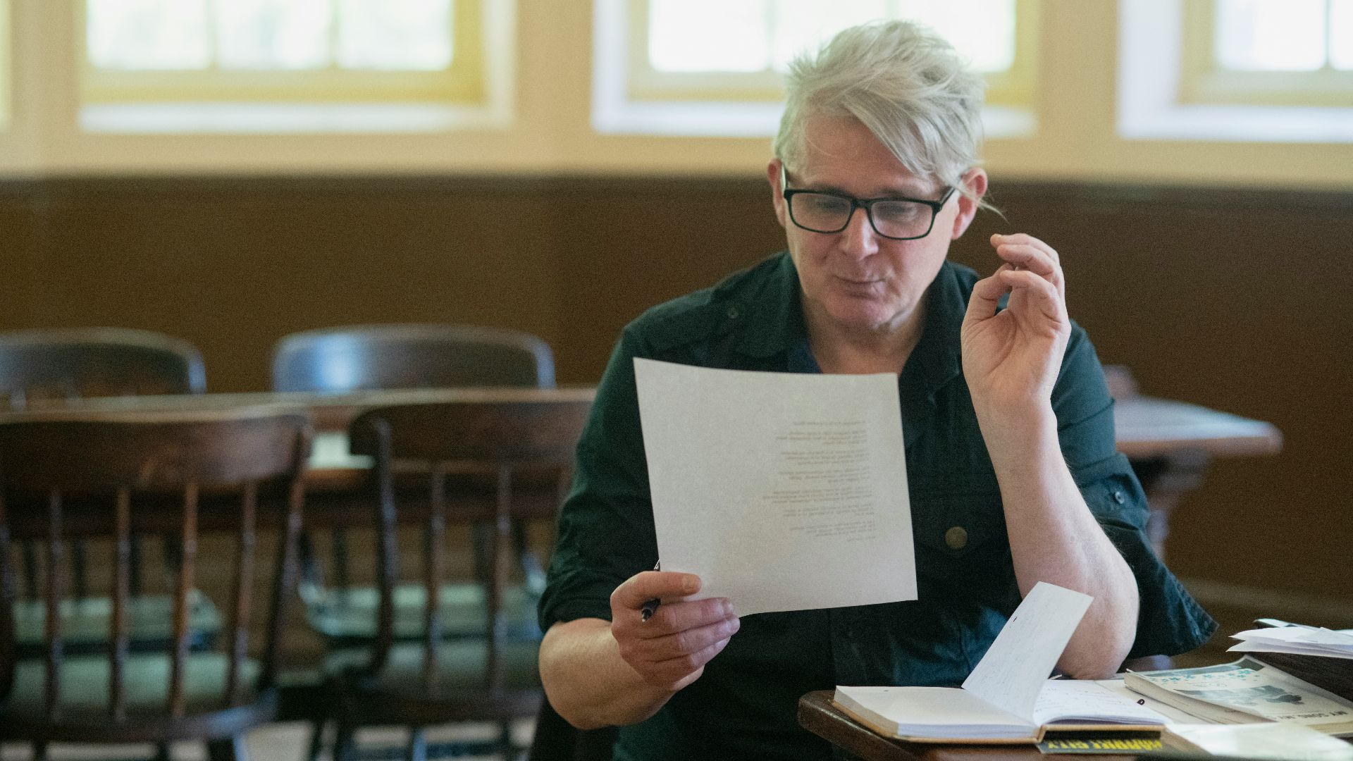 a man sitting at a table holding a piece of paper