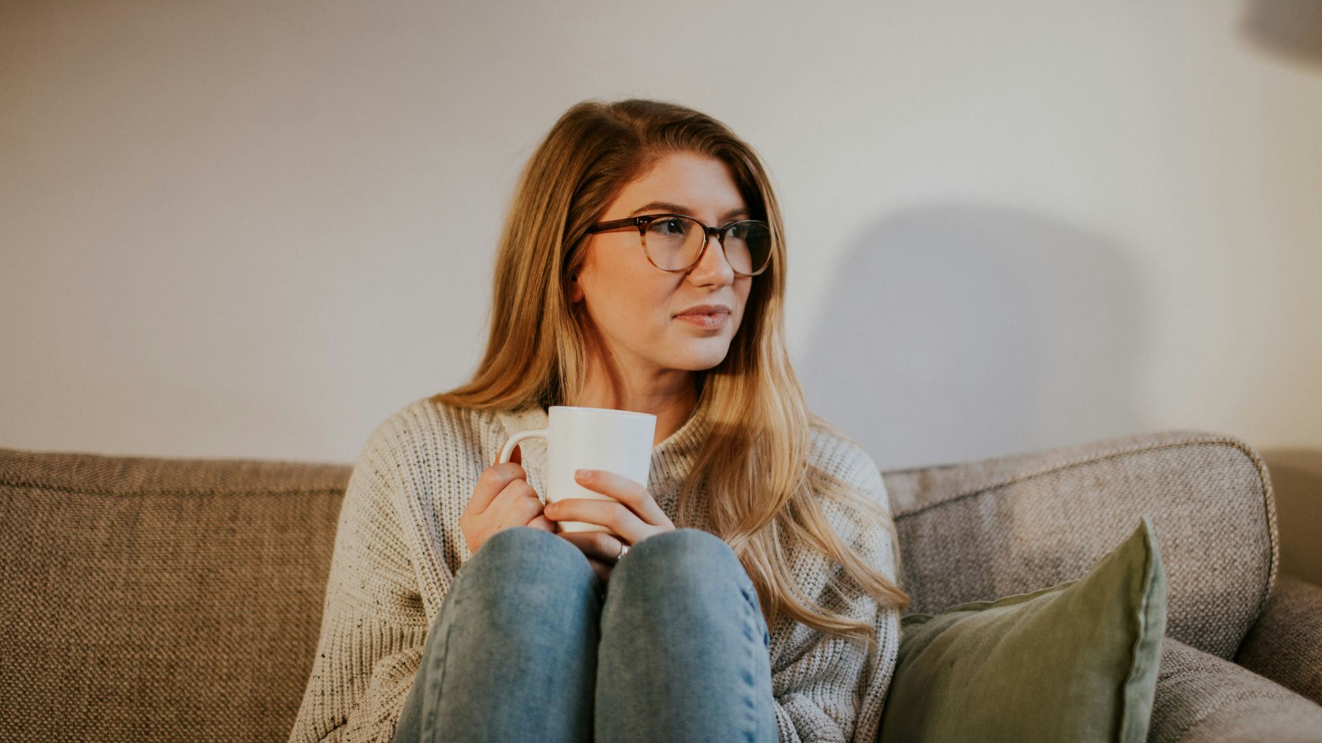 woman in blue denim jeans sitting on gray sofa