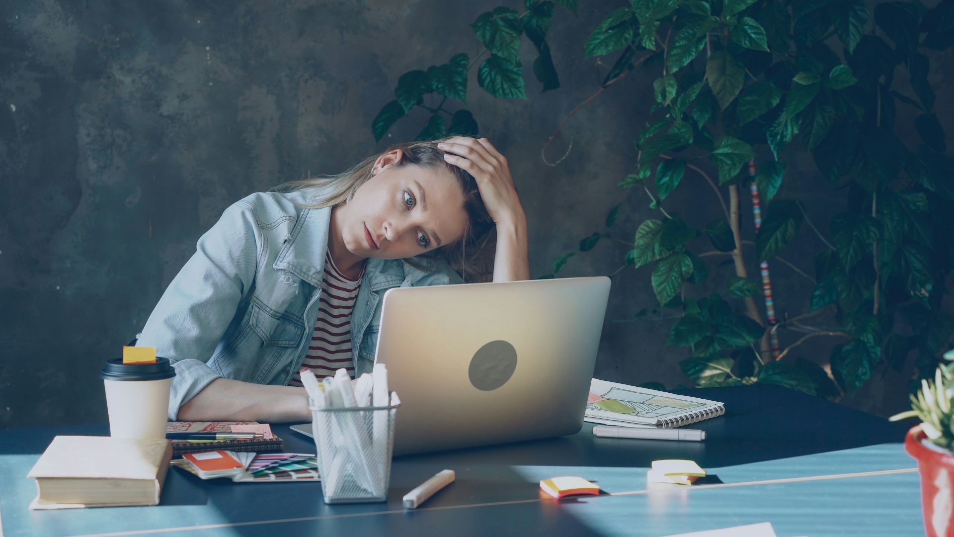 A woman appears stressed while working on laptop.