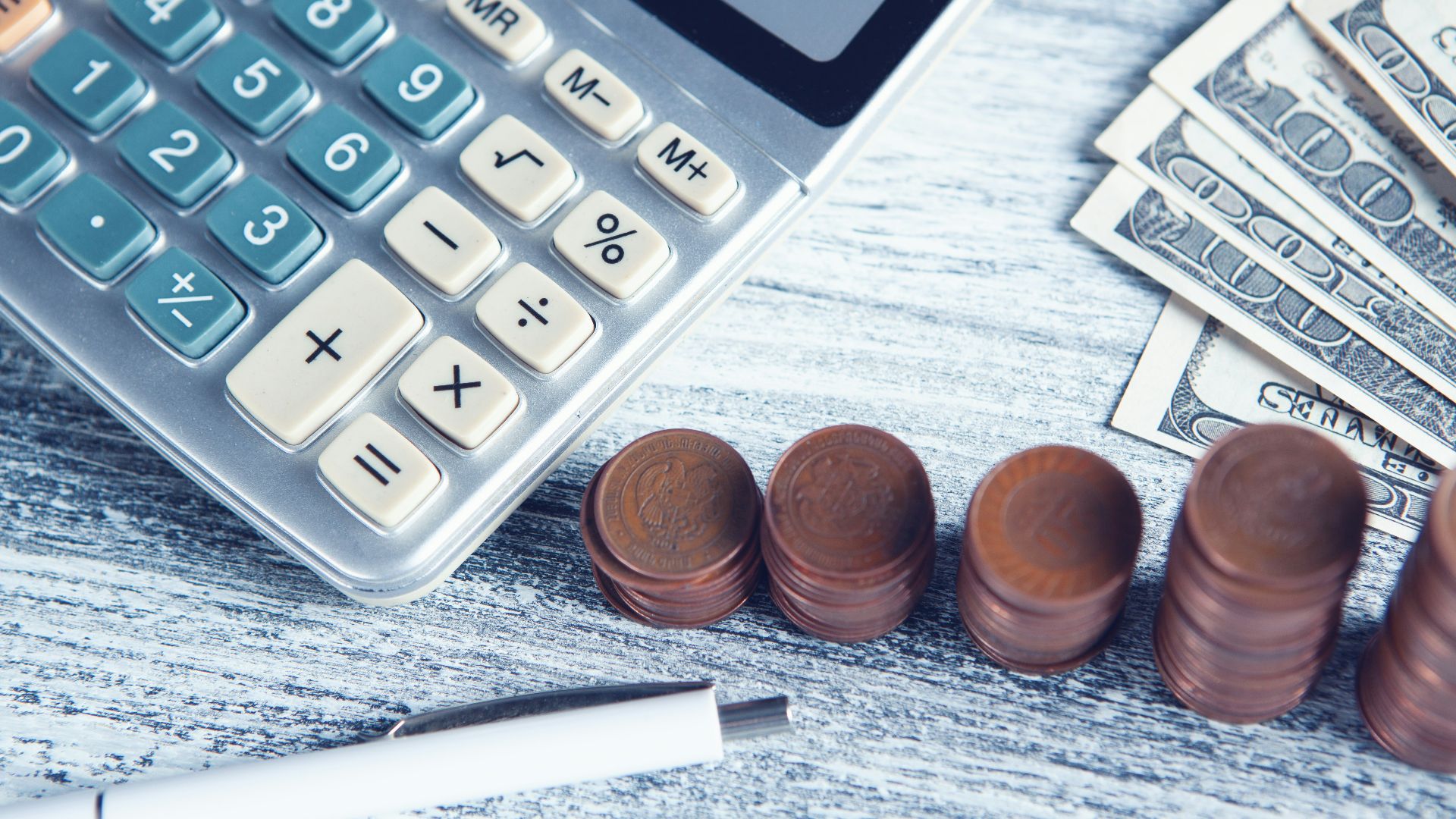 a calculator, pen, and money on a table
