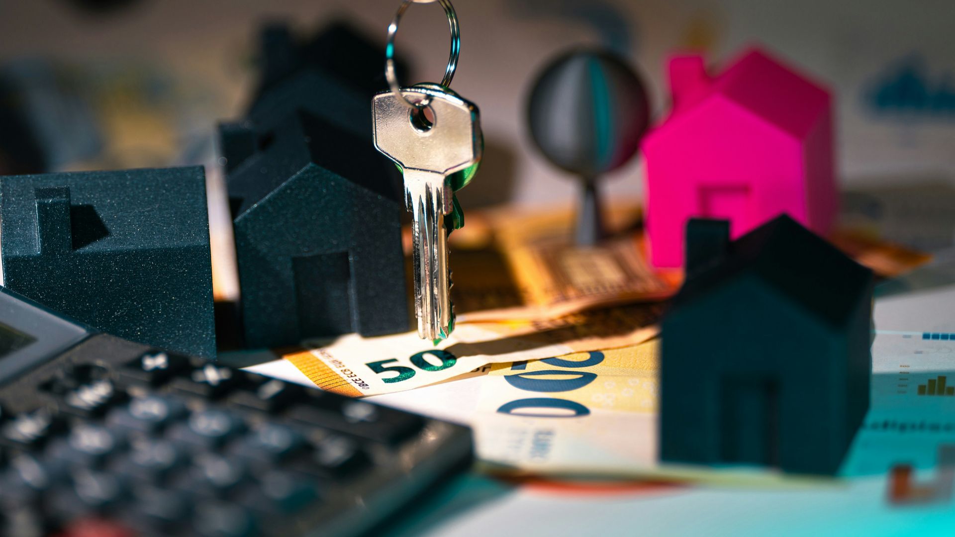 A calculator, keychain, and house model on a table