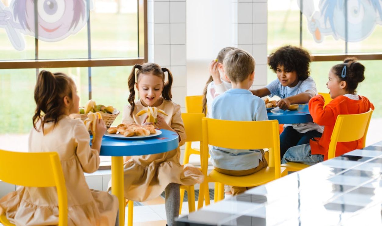 Group of children eating together at a school cafeteria, sharing joy and food.