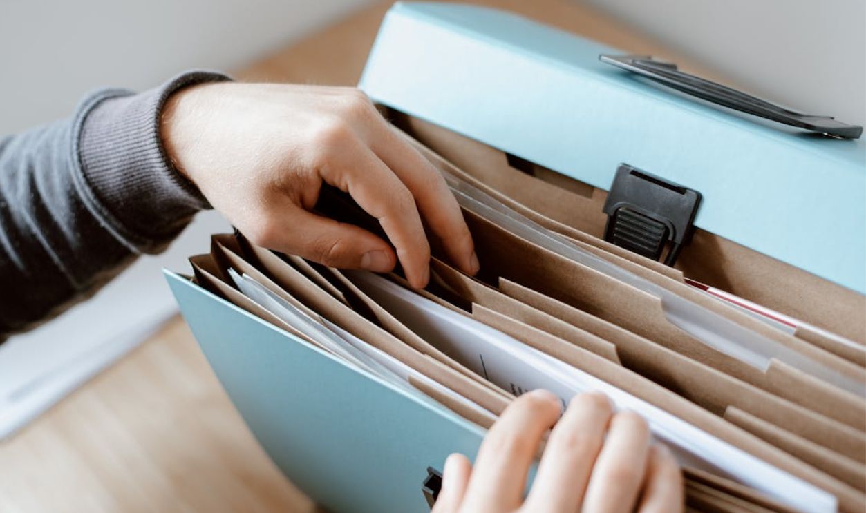 Close-up of hands organizing papers in a blue folder, ideal for business and office concepts.