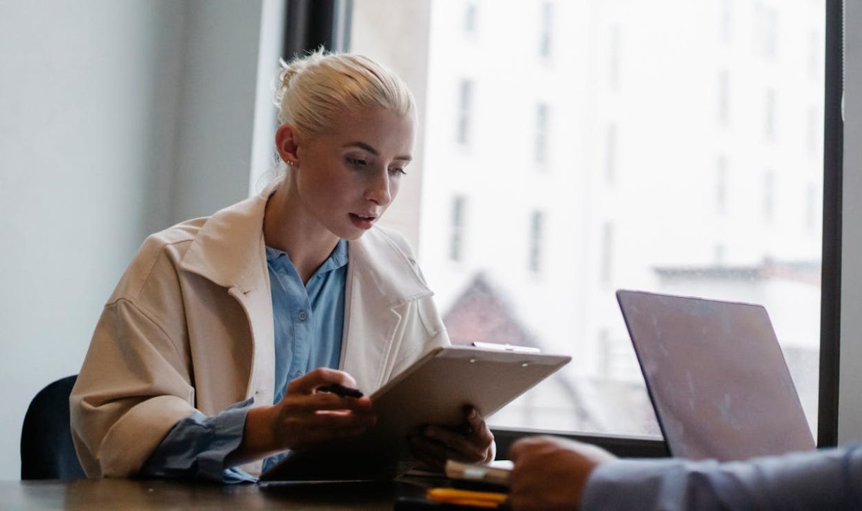 Focused woman analyzing papers during a business meeting in a modern office setting.