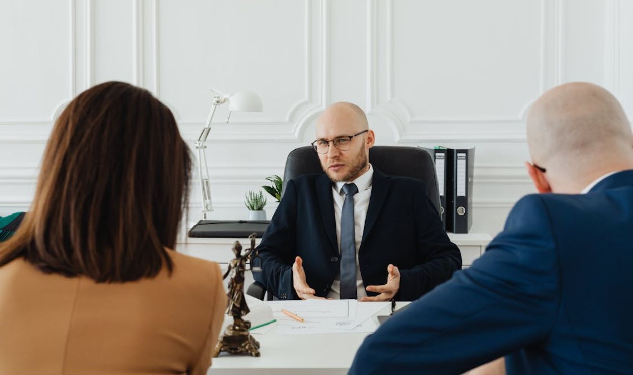 A professional business meeting with a lawyer and clients in a modern office setting.