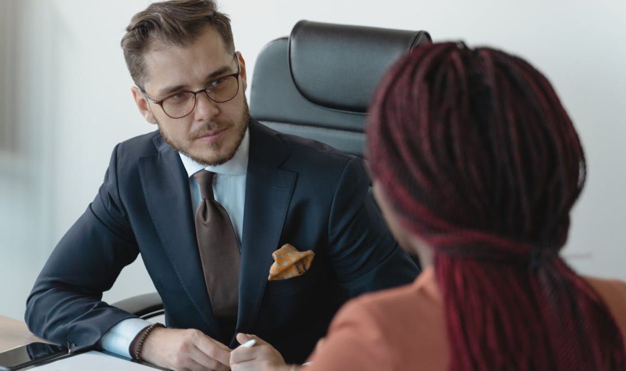 Two professionals engage in a serious discussion at a corporate meeting.