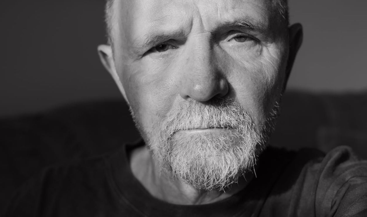 Close-up monochrome portrait of a thoughtful elderly man with facial hair