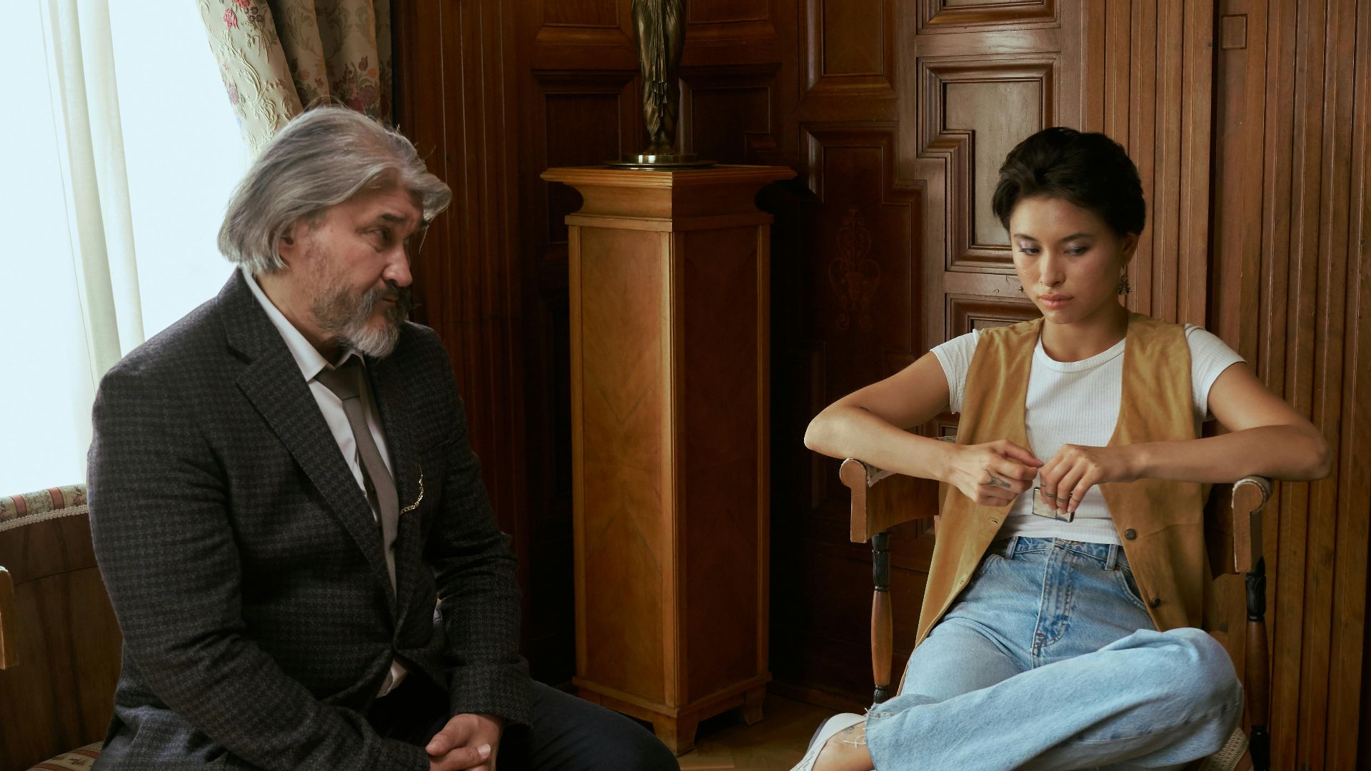A father and daughter engaging in conversation in a luxurious living room setting.