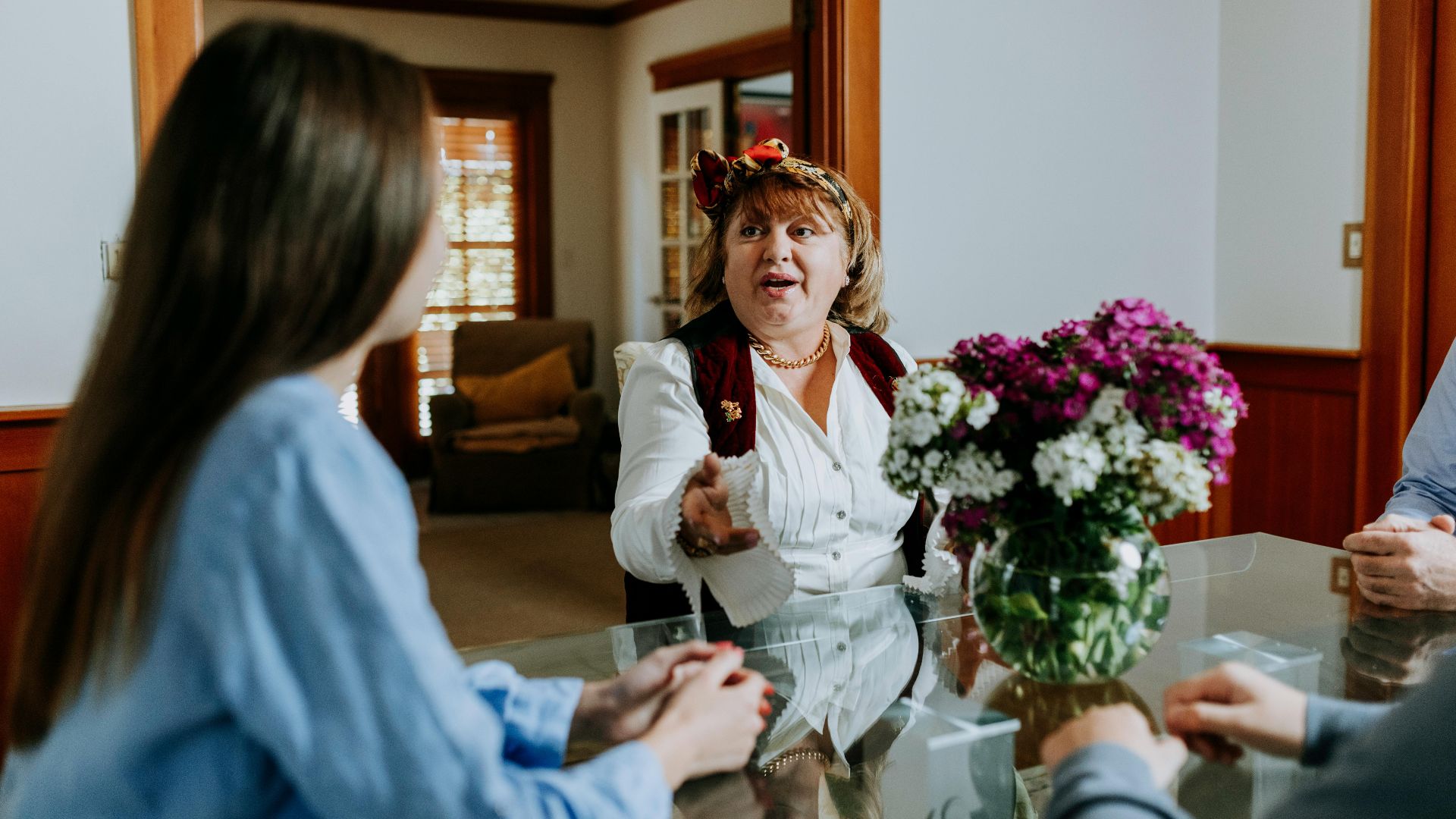 Joyful conversation during a family gathering indoors with a floral centerpiece on a glass table.