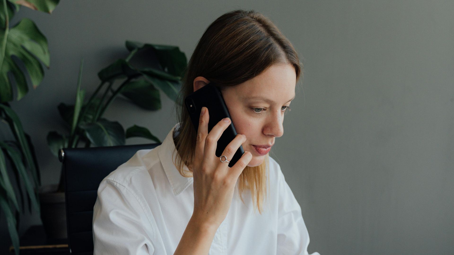 Focused woman architect discussing floor plans on the phone in an office setting.
