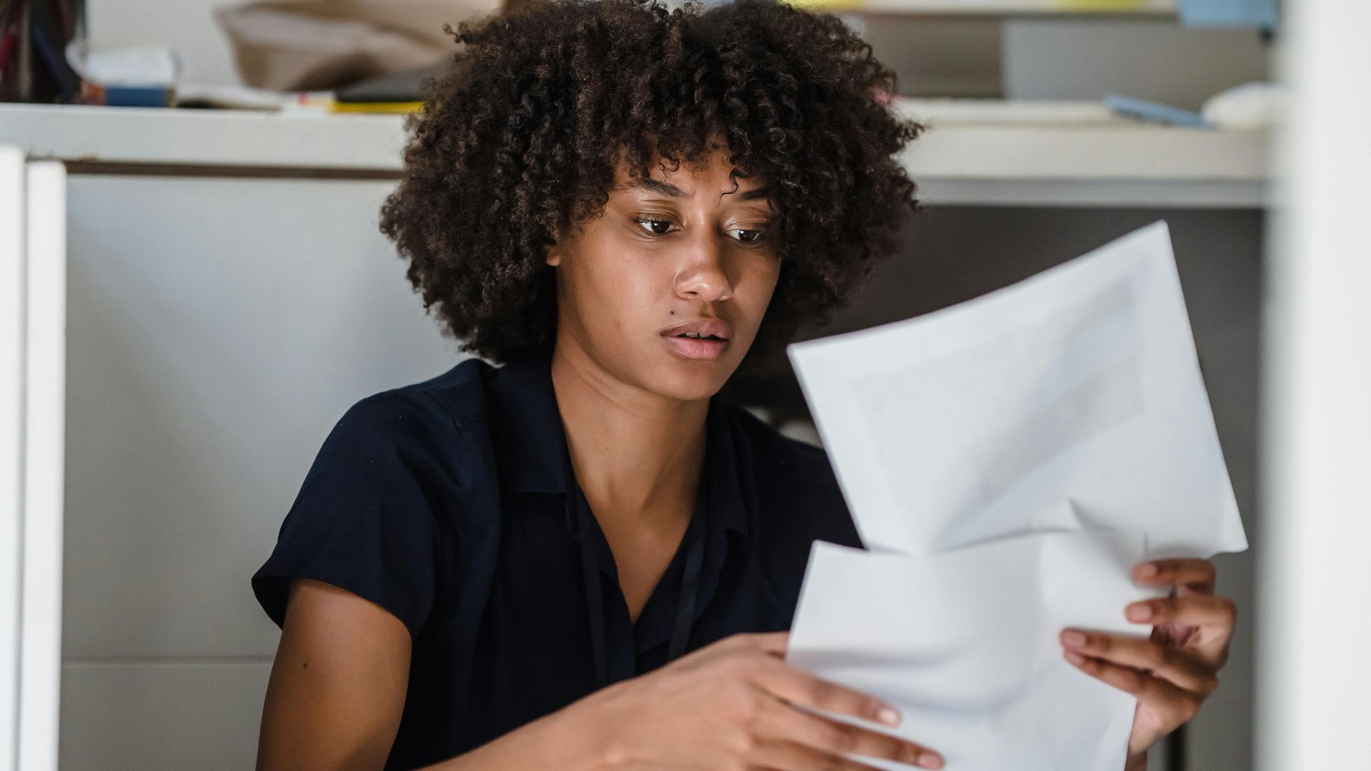 An African American businesswoman reviewing documents on the office floor.