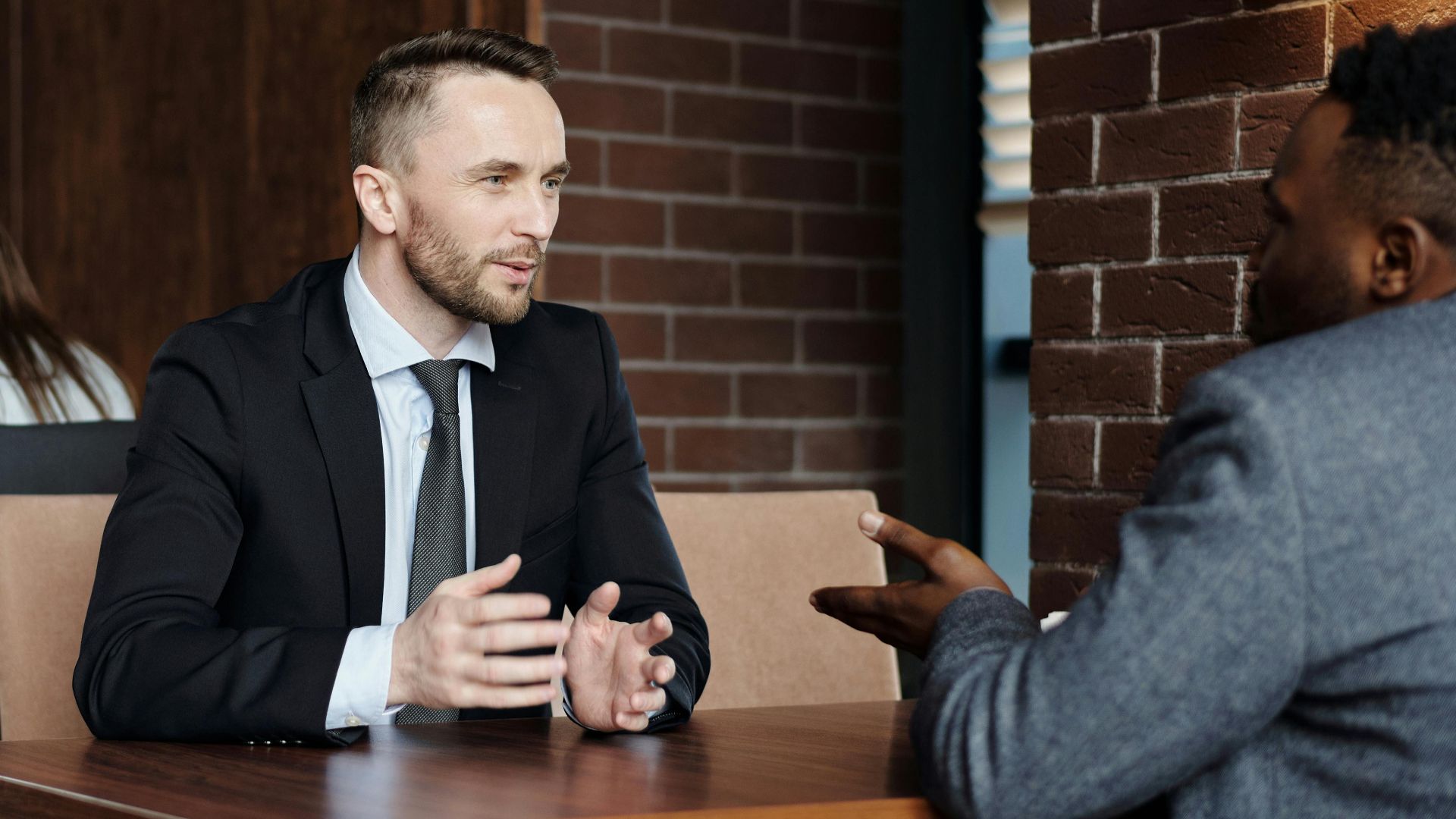 Businessmen engaged in a professional conversation in a stylish café setting.