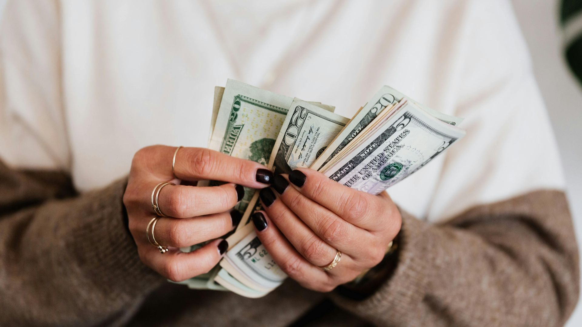 Hands holding and counting US dollar bills, highlighting finance and cash flow.