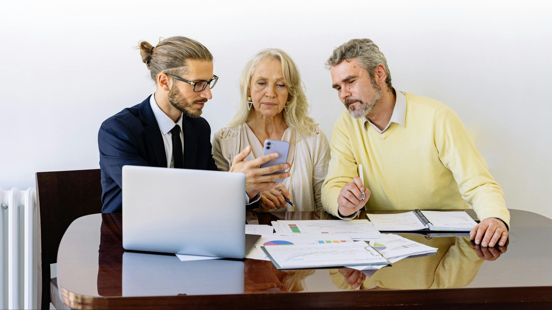 Three individuals collaborating on financial documents during a business meeting.