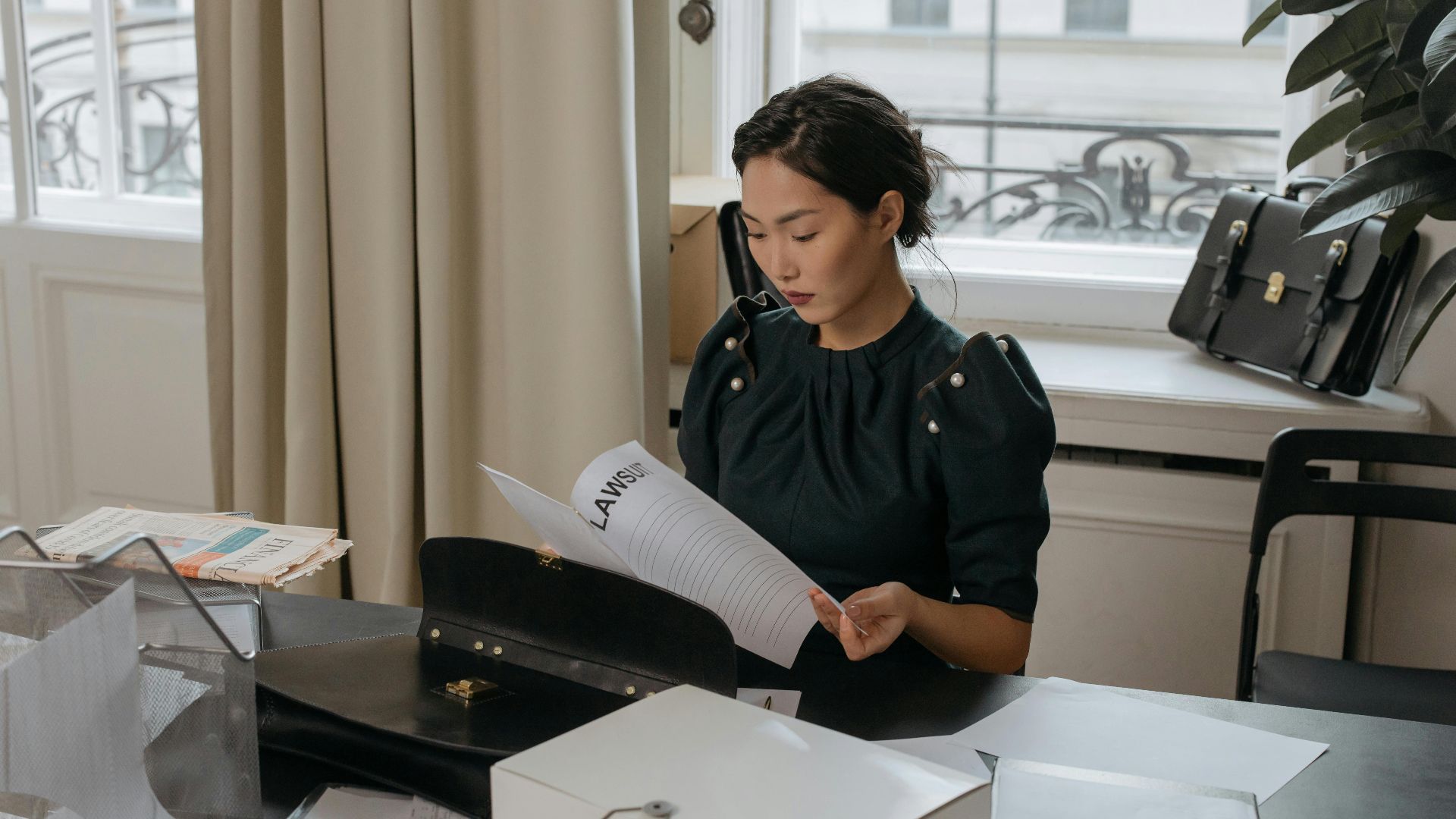 Elegant young woman reading documents in a stylish office setting.