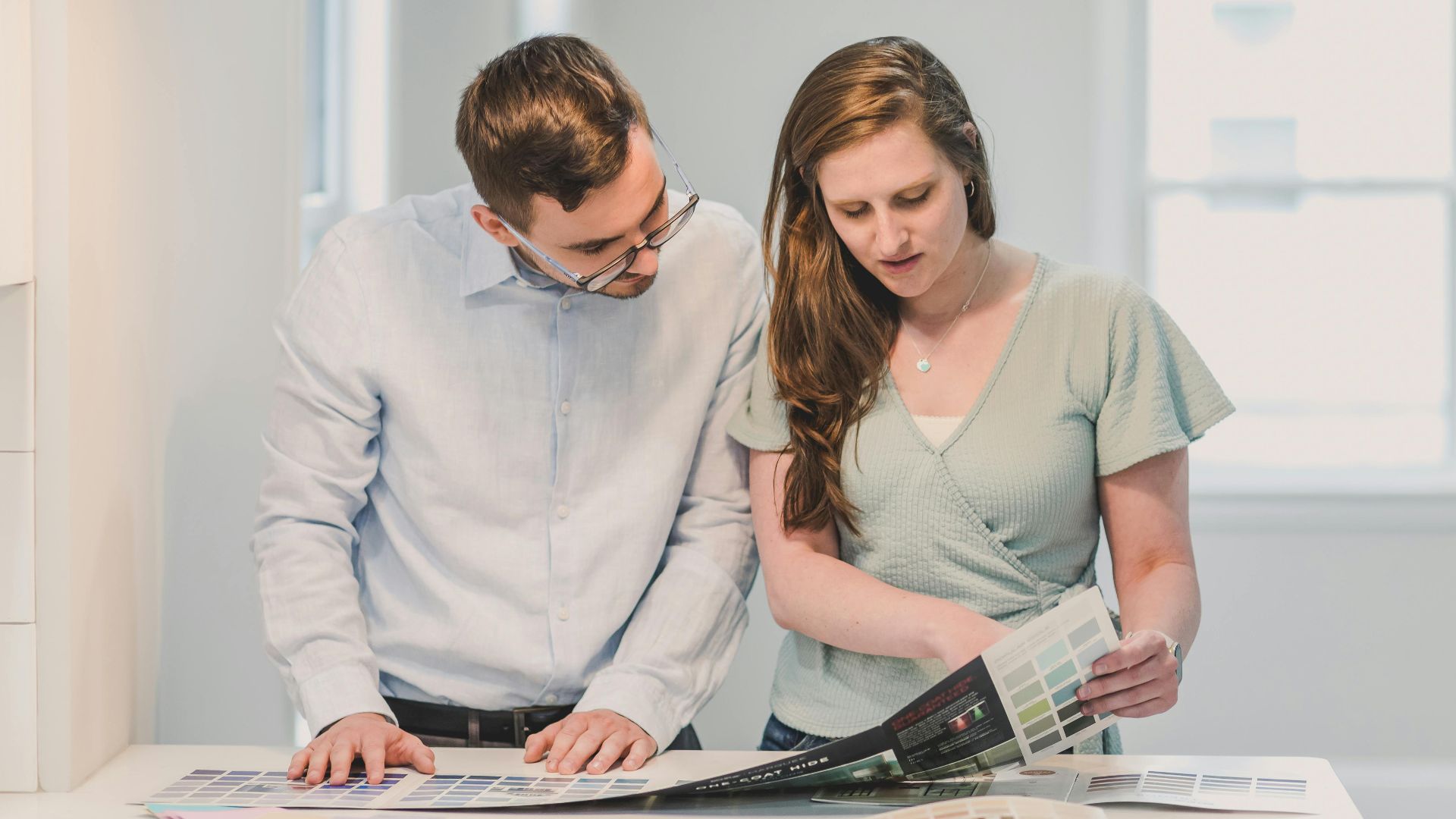 A man and a woman reviewing design samples together in an indoor setting.