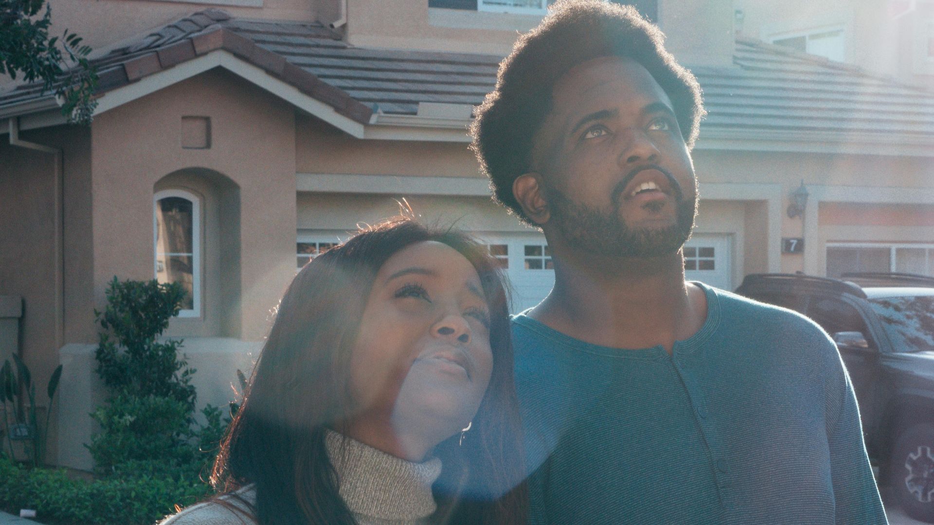 A couple joyfully standing in front of their new home, symbolizing new beginnings and home ownership.