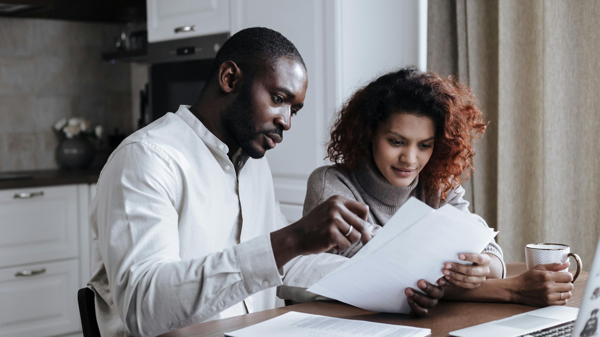 Couple working together on documents at home interior using a laptop.