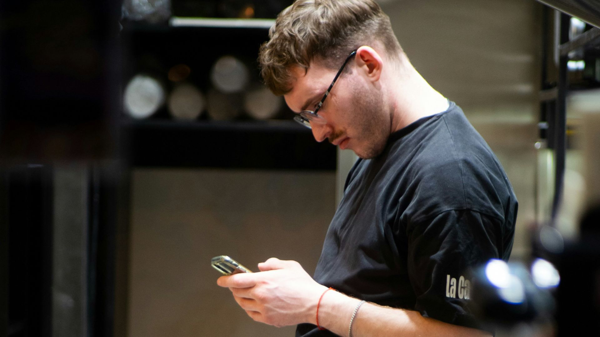 A man standing in a kitchen looking at his cell phone