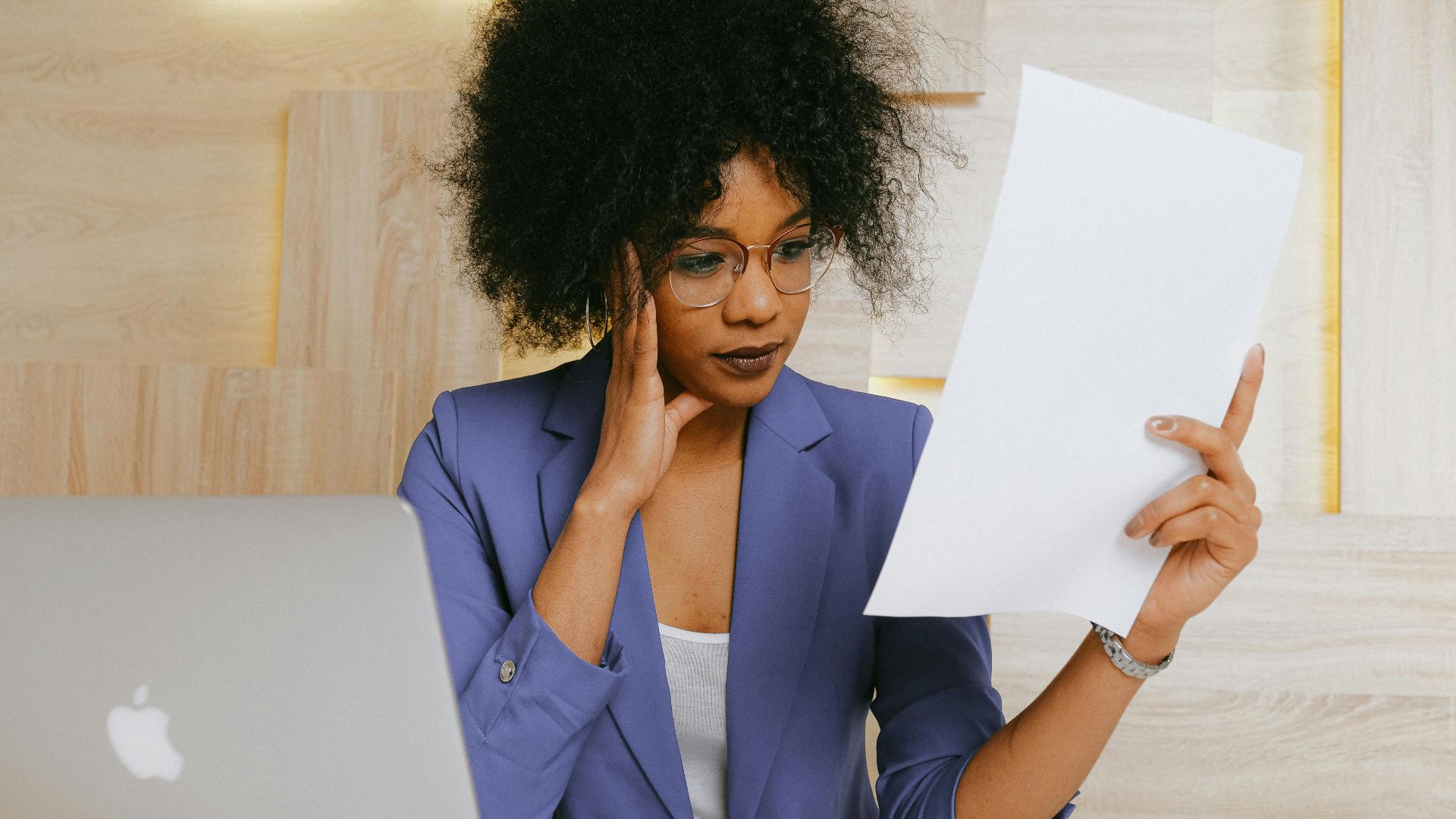 Businesswoman working on a laptop and reviewing a document at the office.