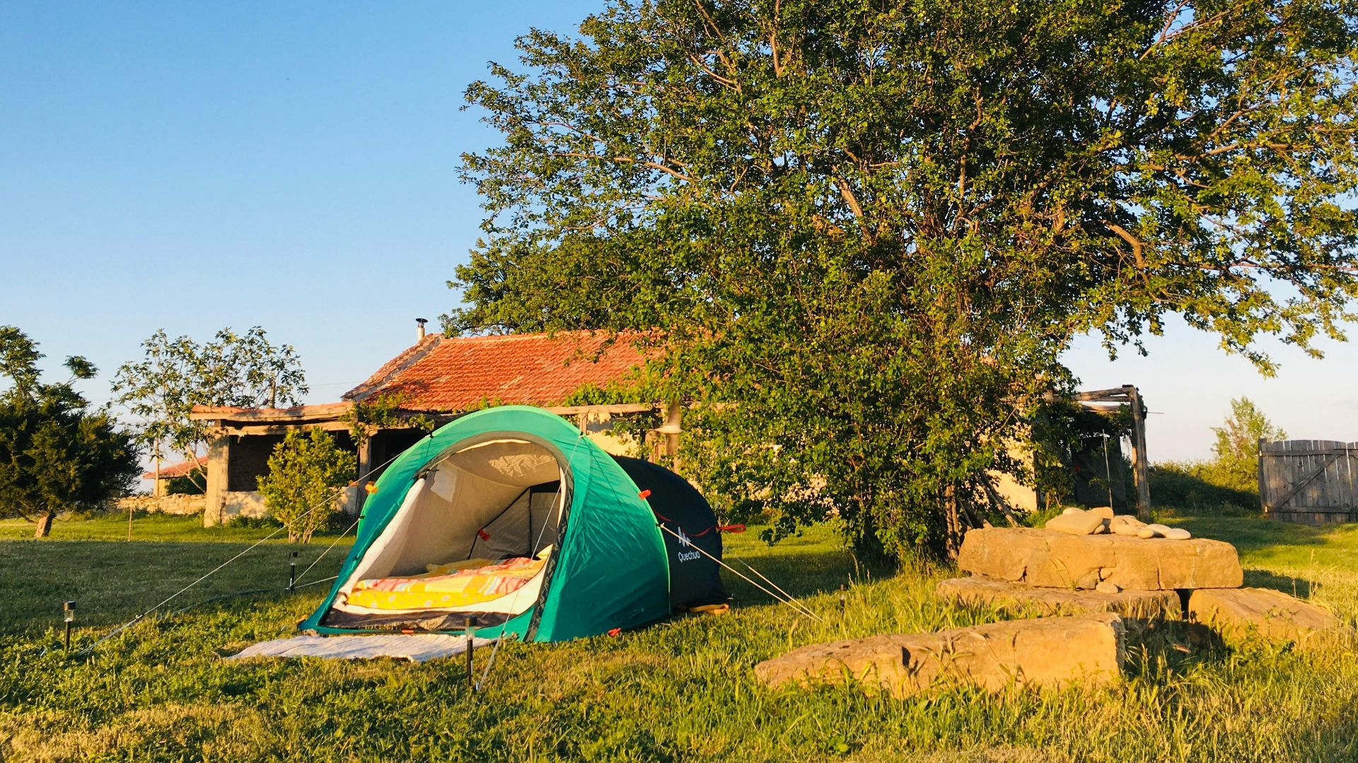 A serene campsite with a green tent and rustic building in Burgas, Bulgaria.