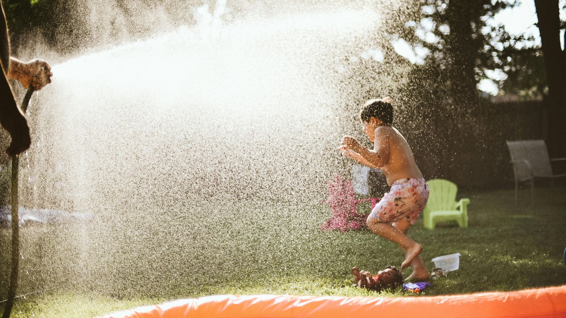 Boy enjoying water spray in backyard on a sunny summer day, capturing fun and joy.
