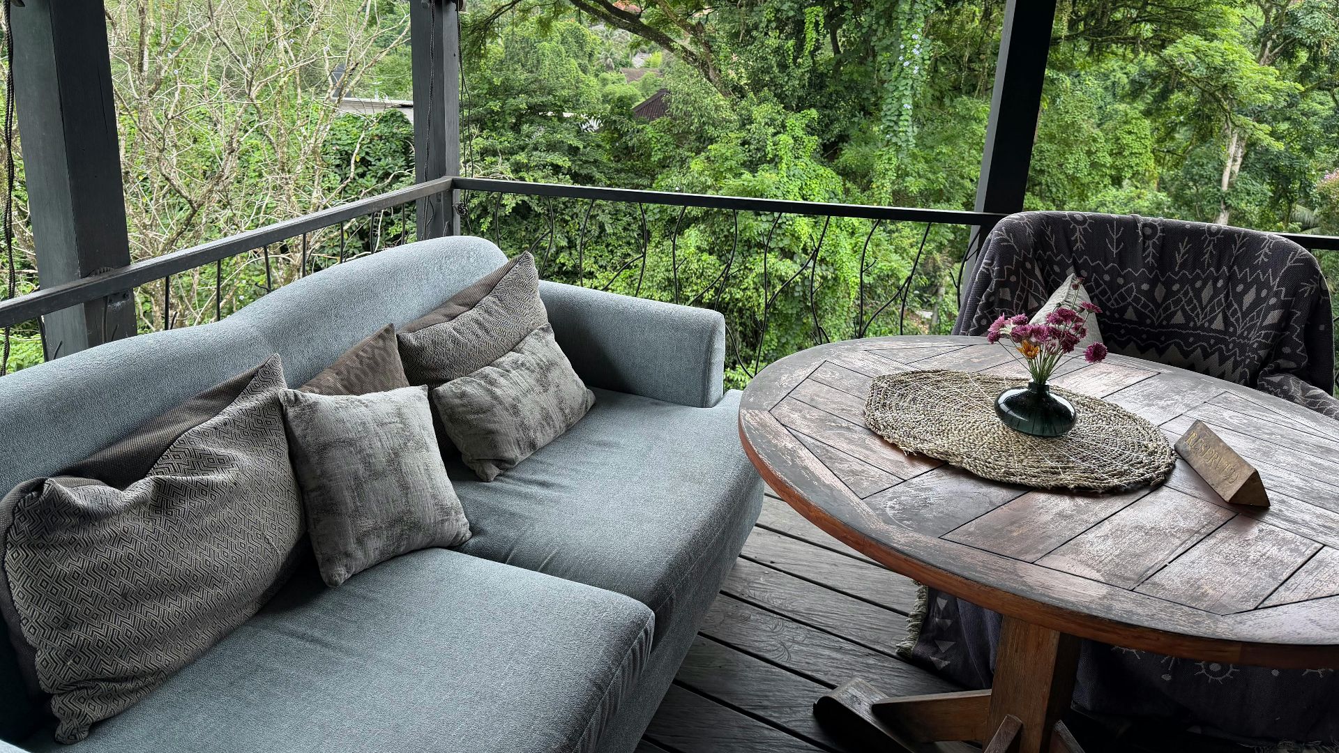Serene outdoor terrace with sofa and table, surrounded by lush greenery.