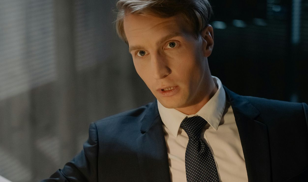 A businessman in a suit sitting at a desk with documents, in an office setting