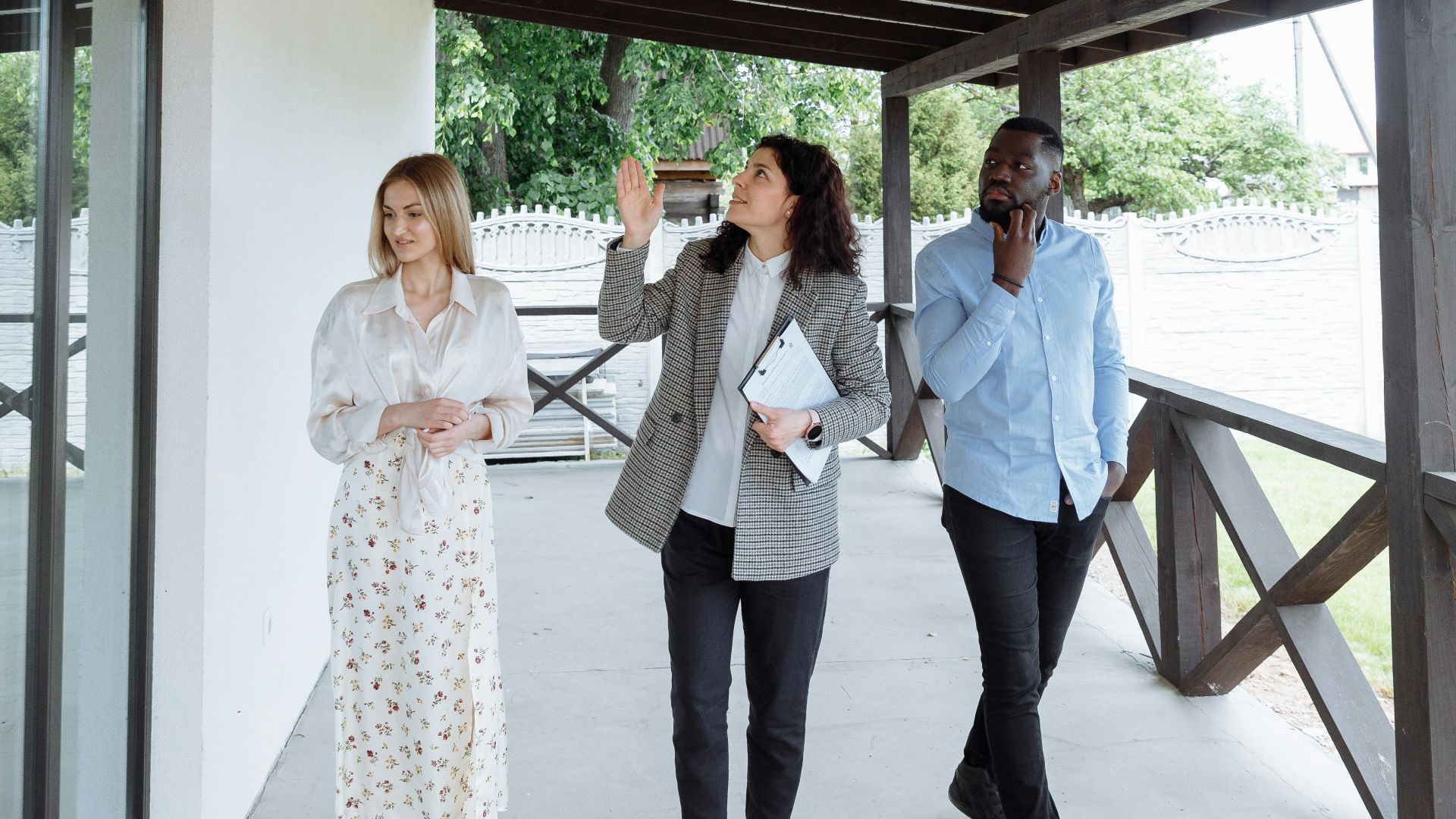 Real estate agent showing house to clients during walk-through on a porch.