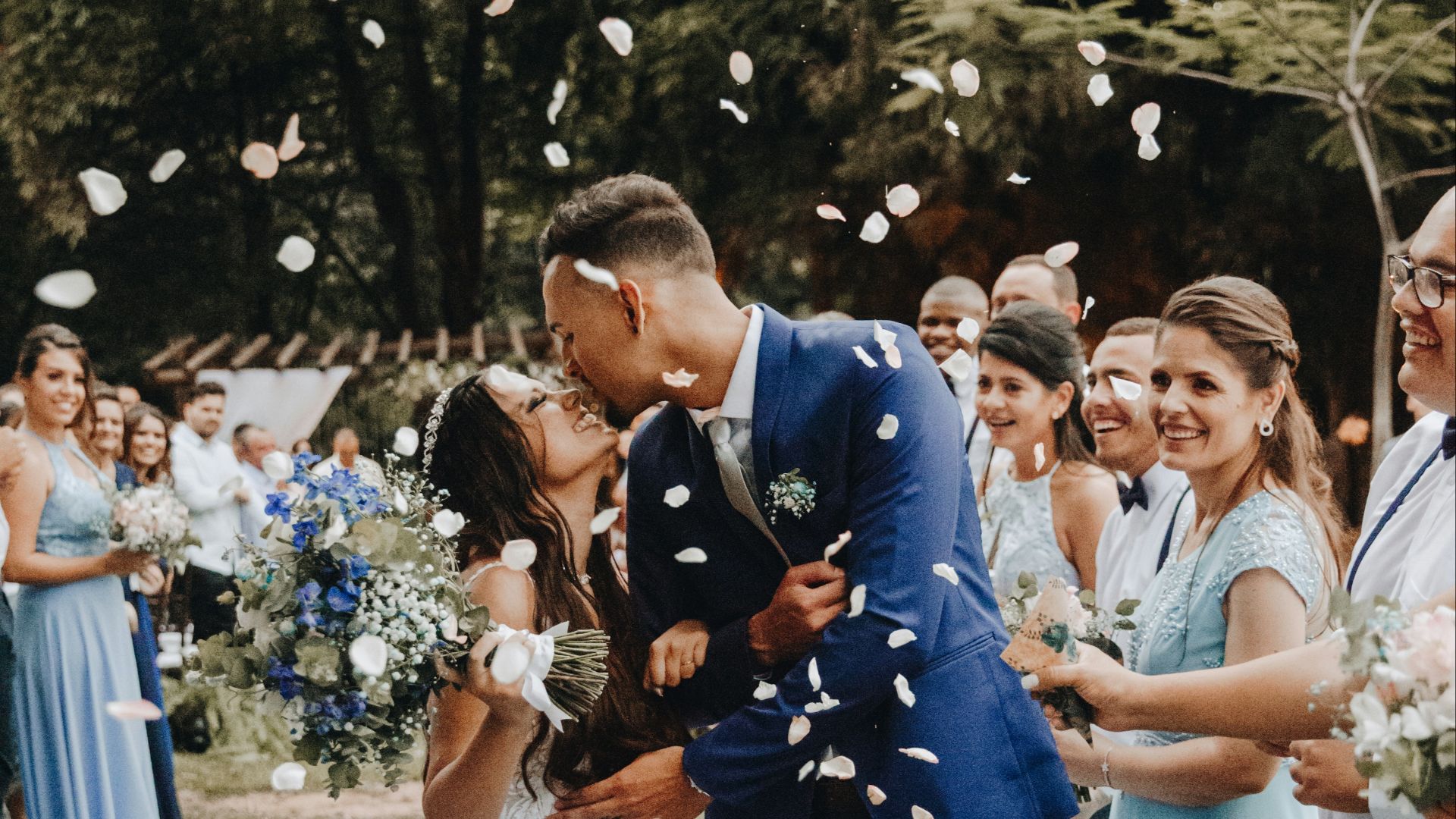 man in blue suit kissing woman in white wedding dress