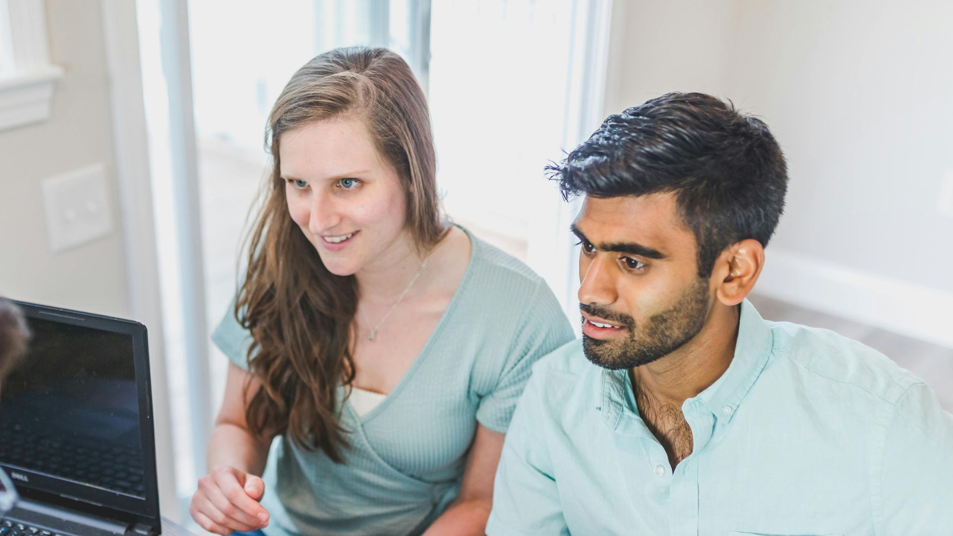 A couple consults with a real estate agent about buying a new home, papers and calculator on the table.