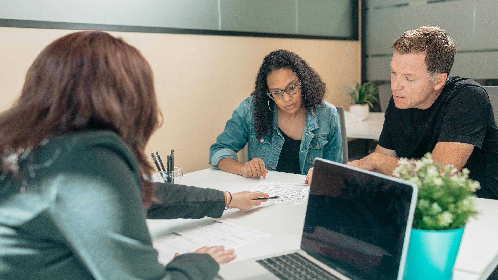 Couple meeting with advisor for adoption process in a modern office setting.
