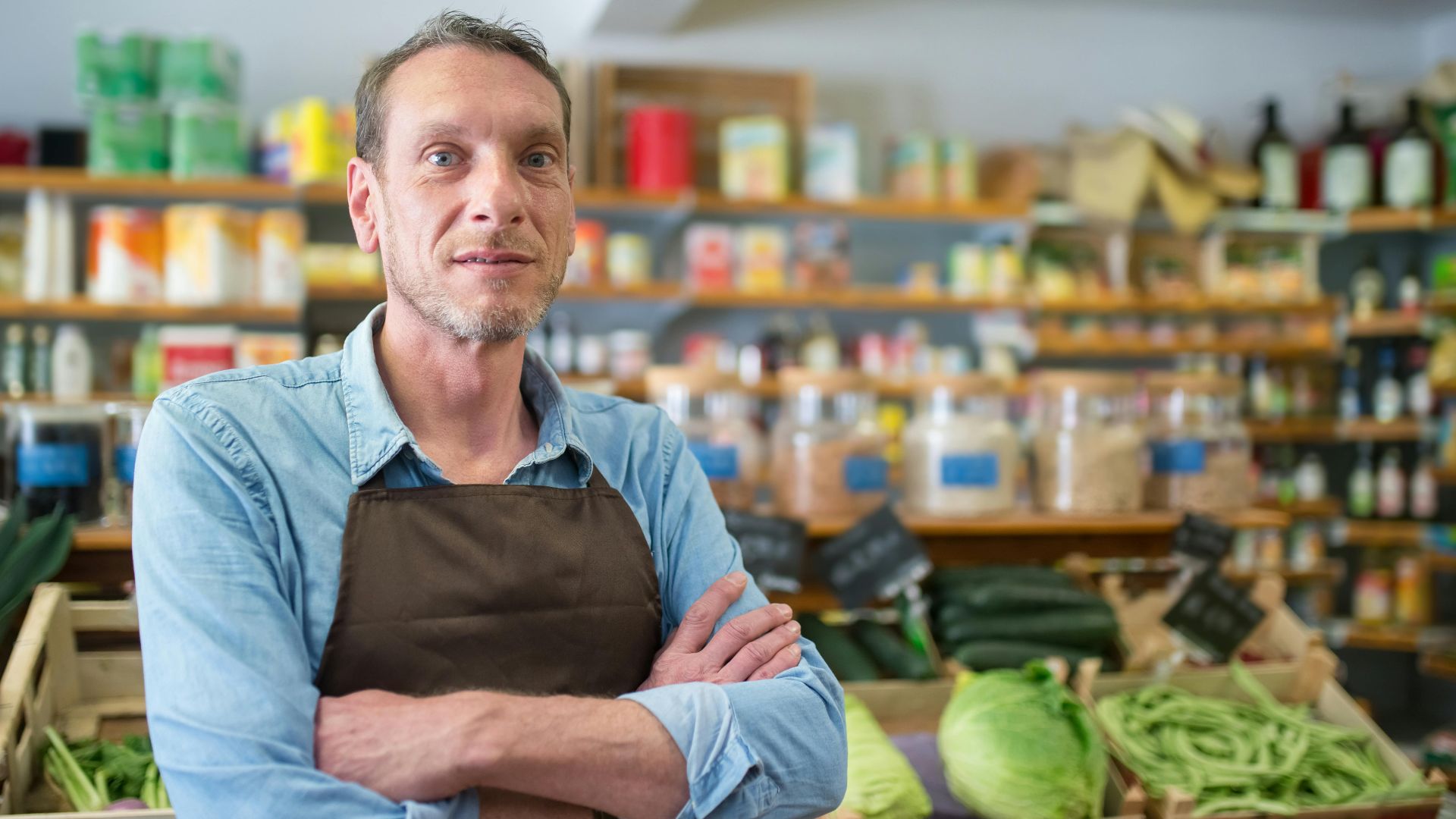 Portrait of a male vendor in a Portuguese grocery store with fresh produce.