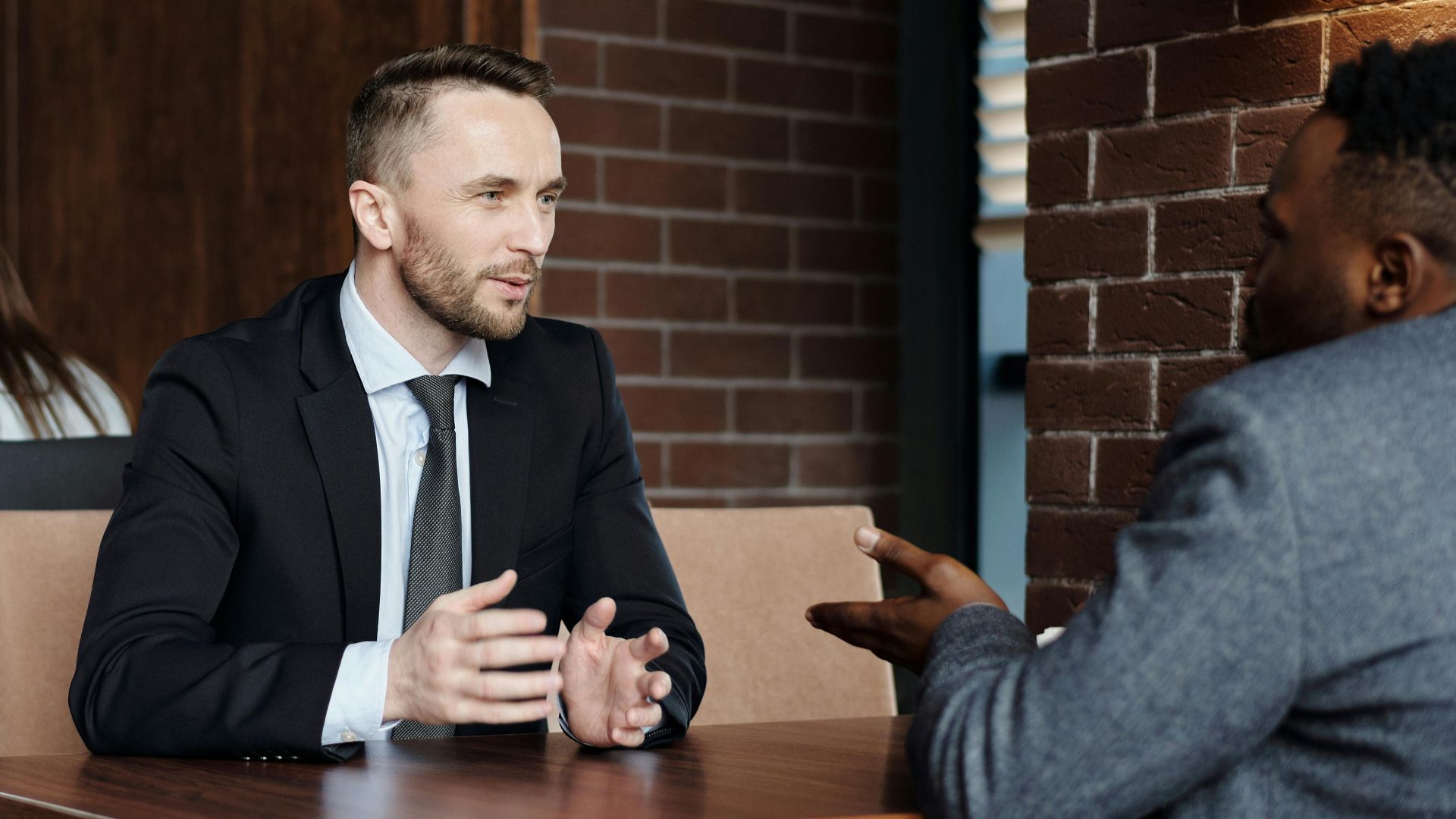 Businessmen engaged in a professional conversation in a stylish café setting.