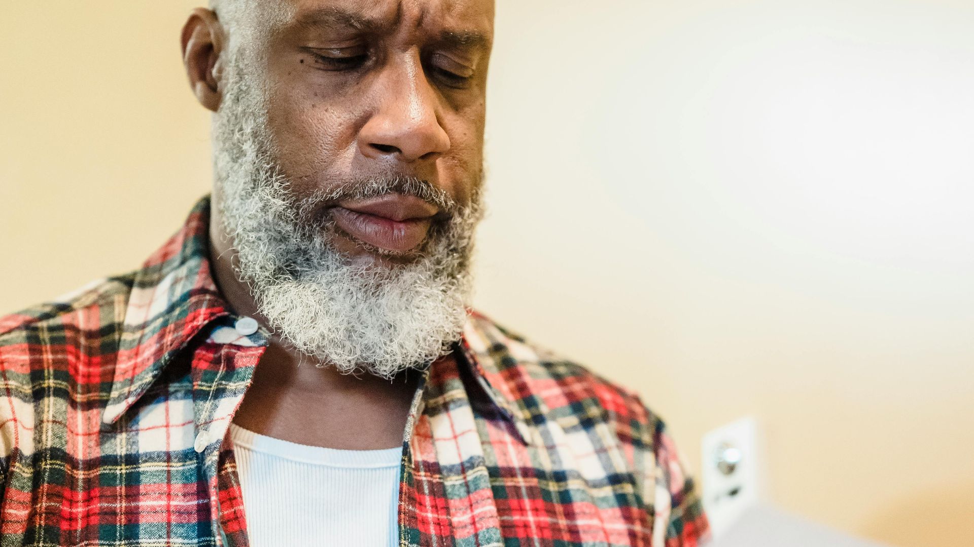 A mature man with a beard attentively reading documents indoors in a focused manner.