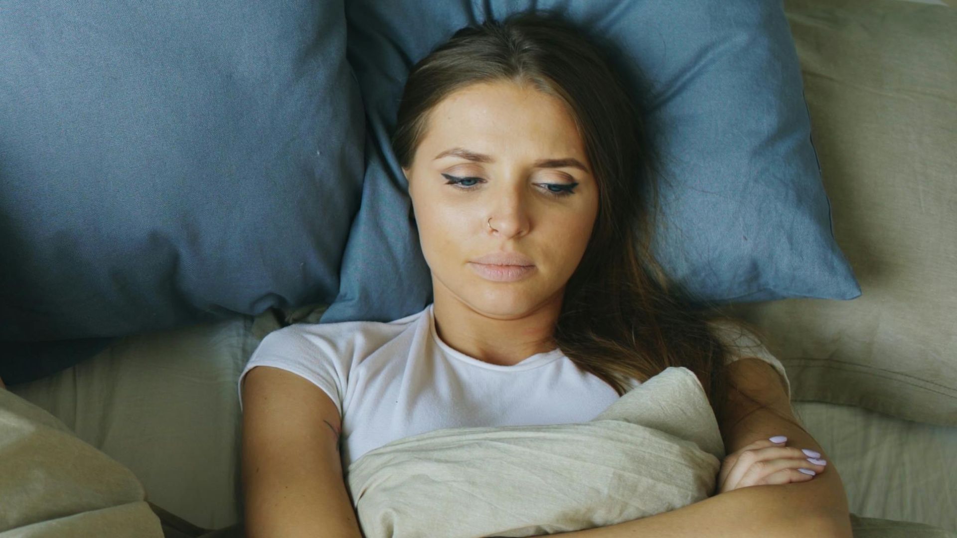 Tense couple lying apart in bed, reflecting relationship strain.