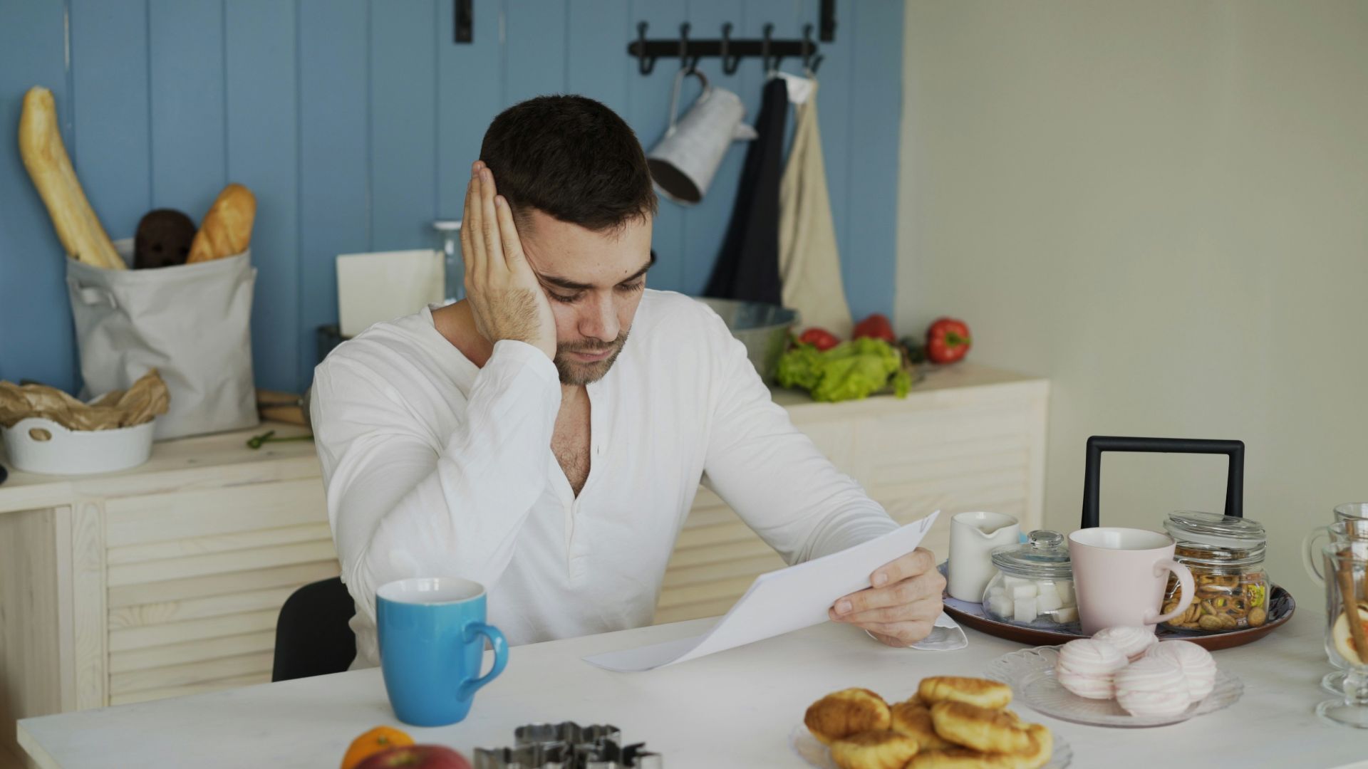 Man sitting at table reading papers with breakfast.