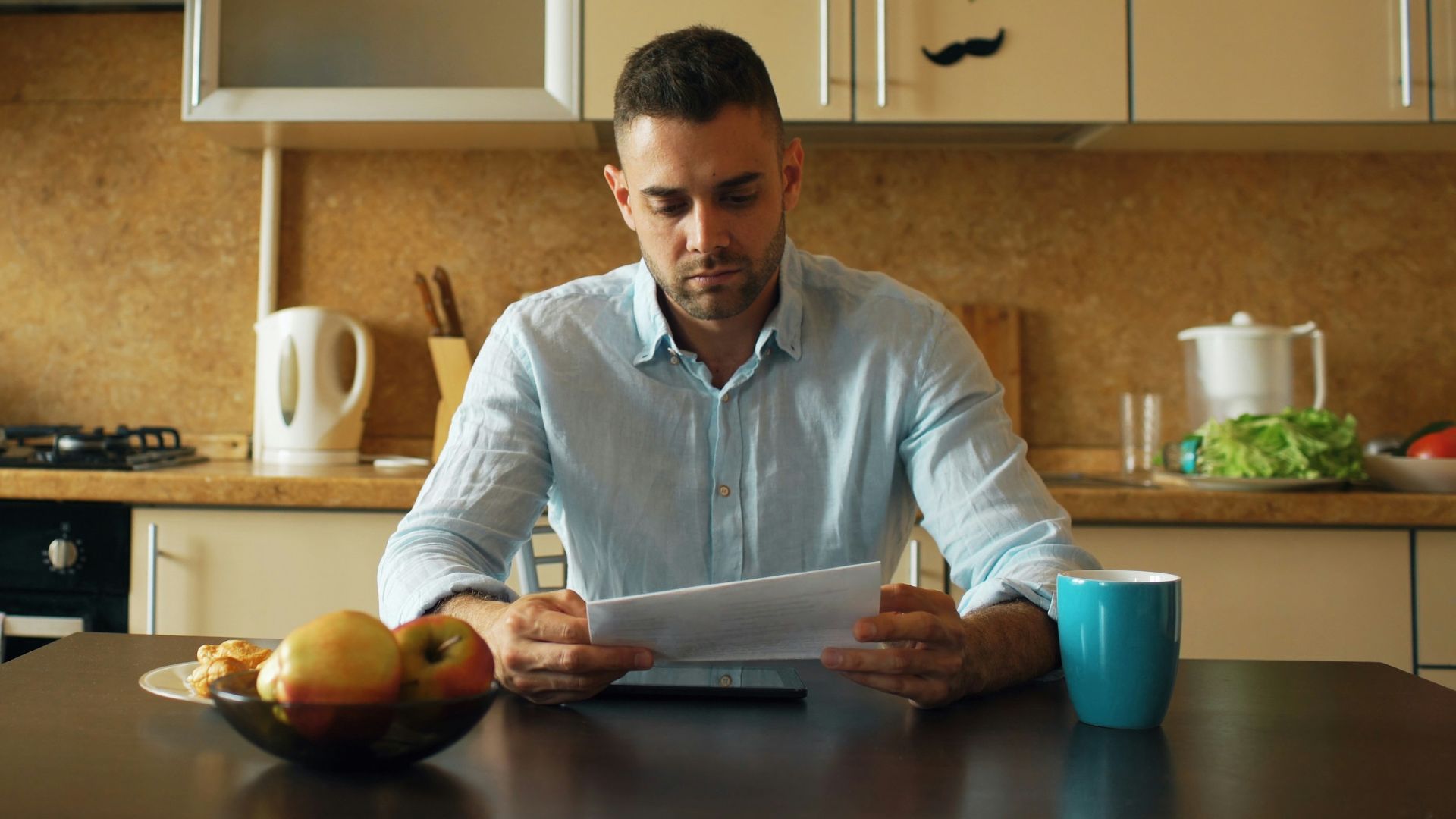 Man reading document at kitchen table with coffee