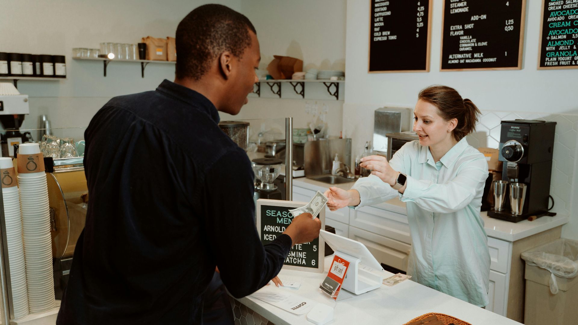 A customer pays for coffee at a café counter, transaction with barista.