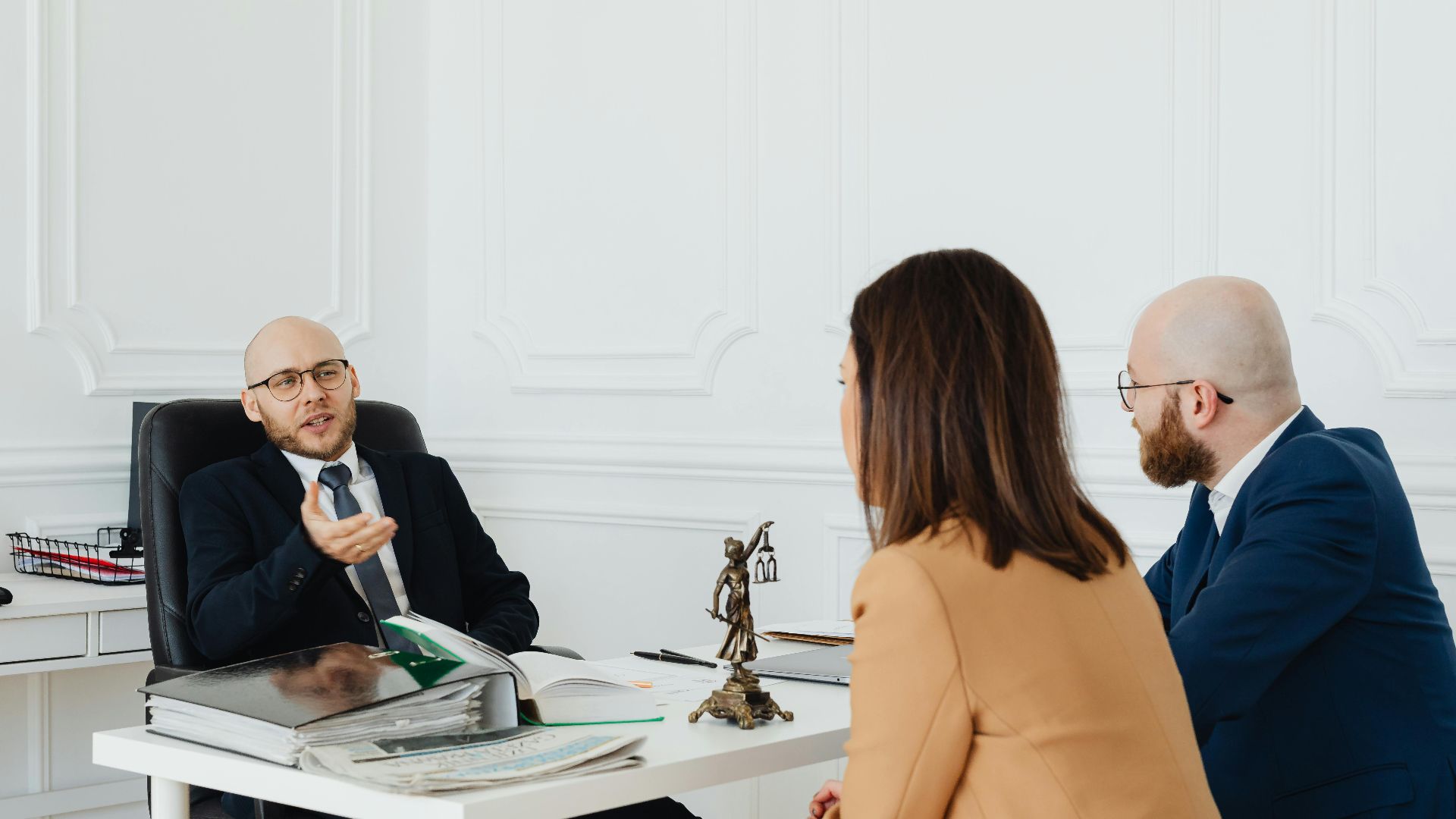Three adults in a formal business meeting discussing legal matters in an office.