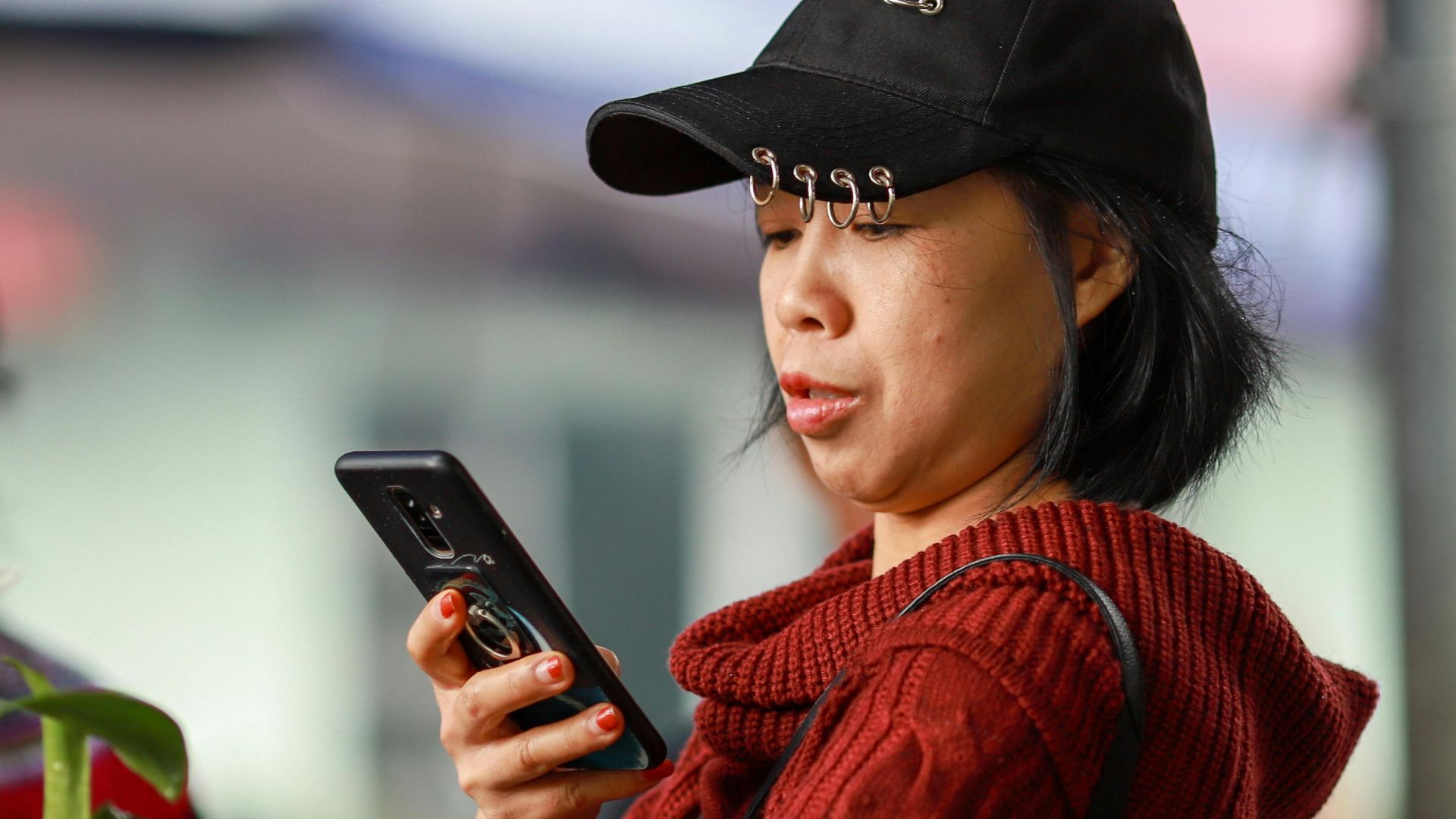 A woman using her smartphone while shopping at the vibrant Lào Cai market in Vietnam.