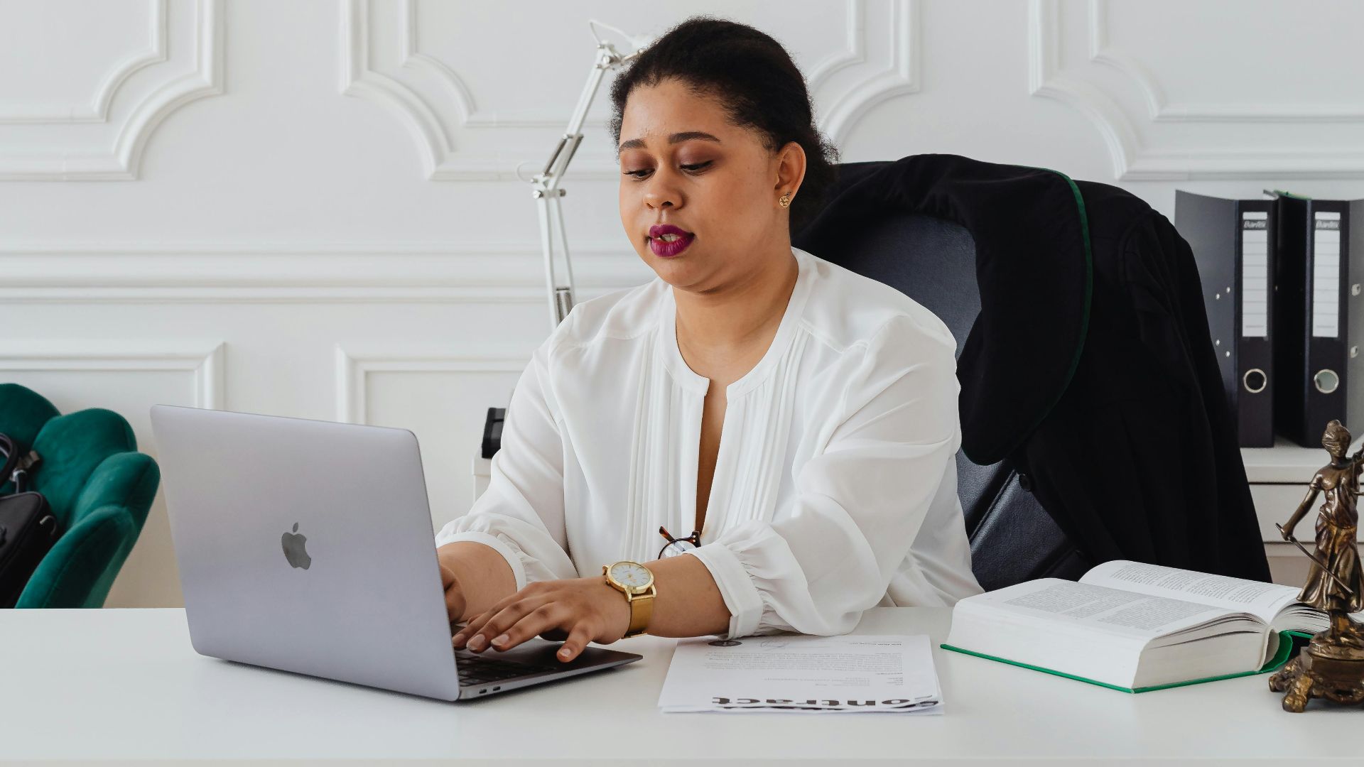 Focused businesswoman using laptop in elegant office setting, showcasing professionalism and modern work environment.