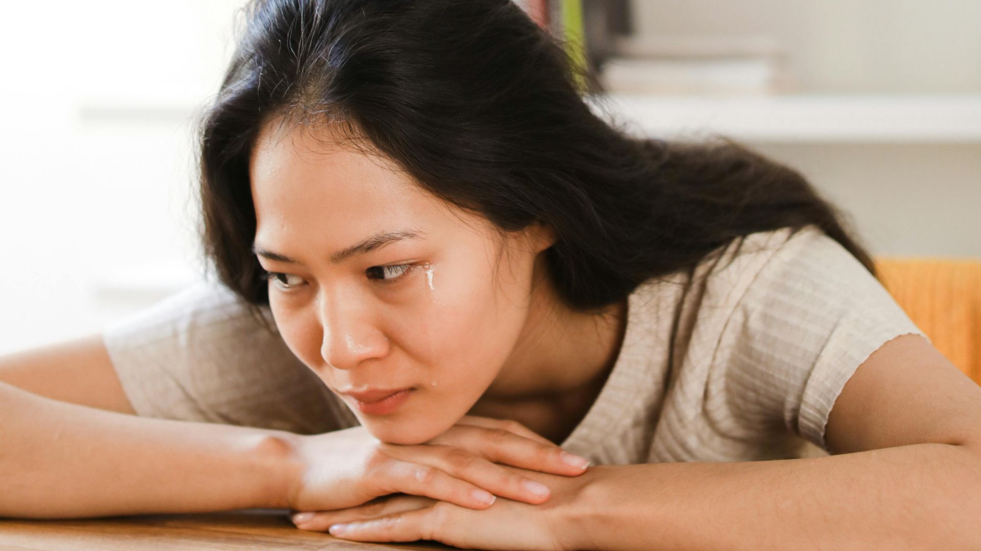 Thoughtful woman gazes at a ring on a table, symbolizing relationship introspection.