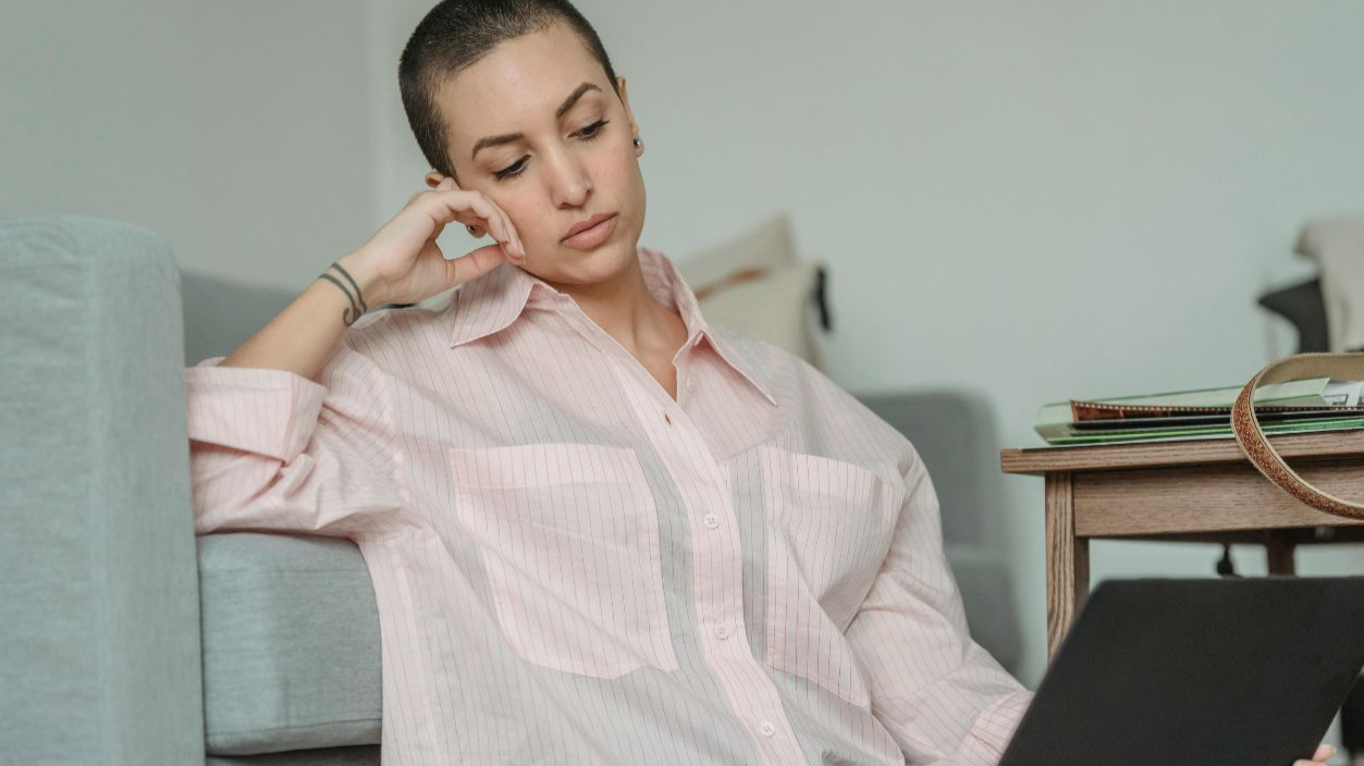Young woman dressed casually using laptop while relaxing at home